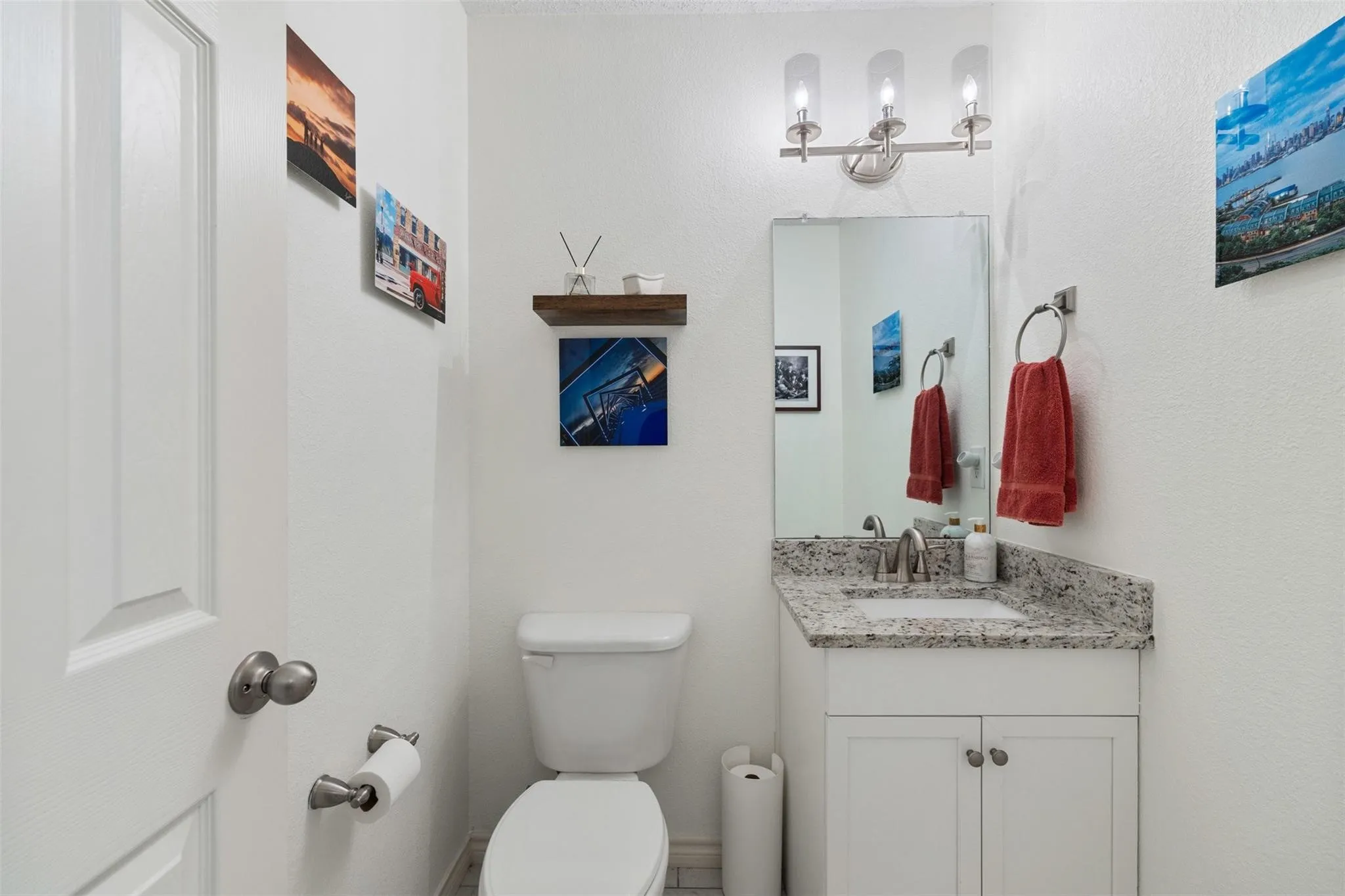 Vanity with a granite countertop and an undermount sink, illuminated by a three-light fixture