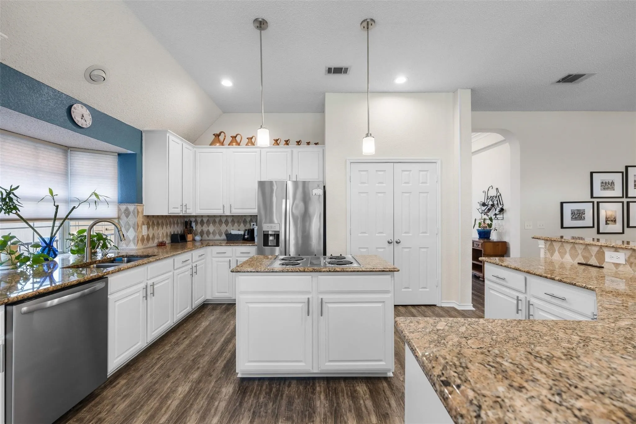 Kitchen featuring white cabinetry, granite countertops, stainless steel appliances, a center island, and wood-finish flooring