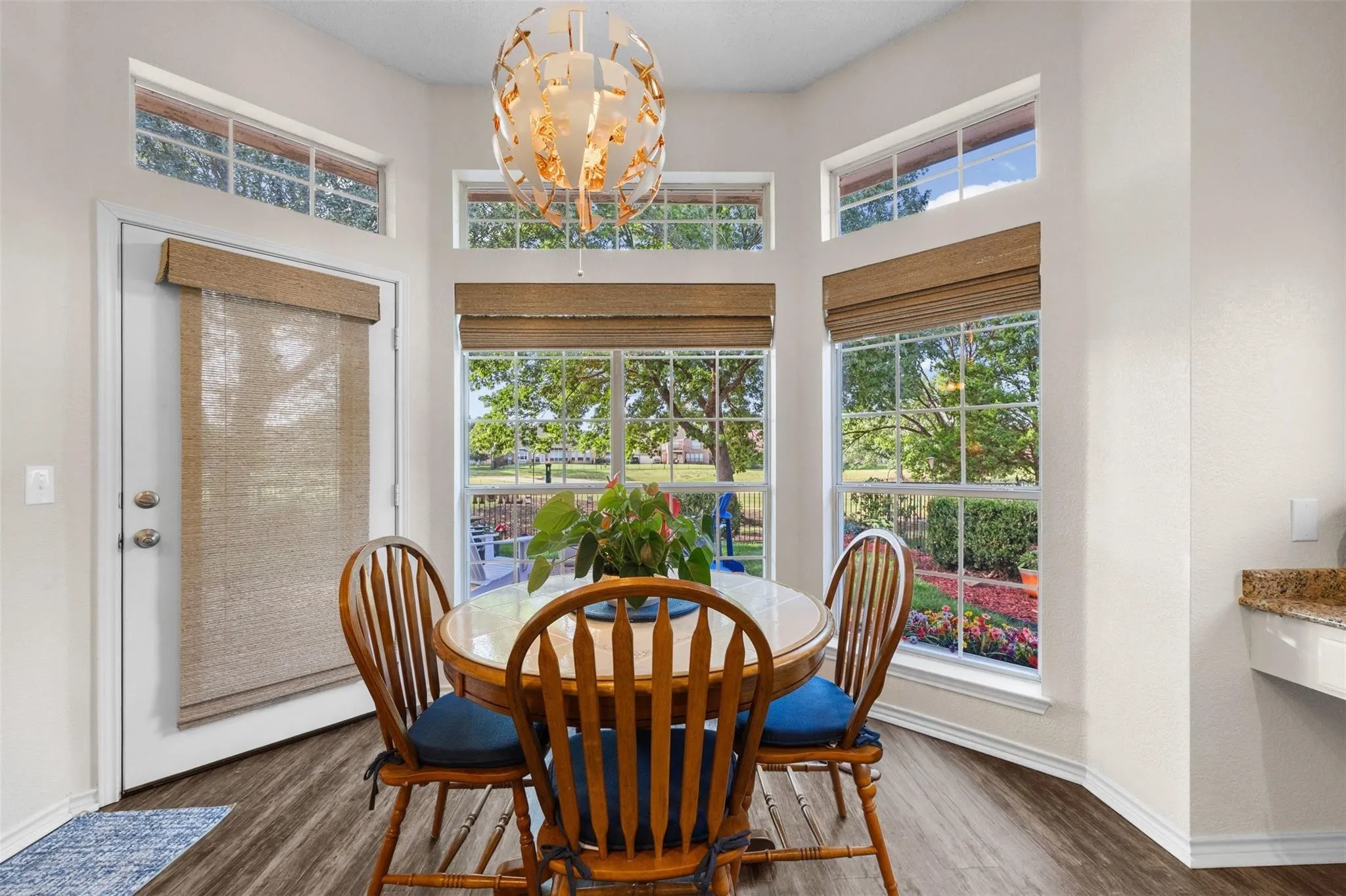Bay window with upper transom windows, wood-finish flooring, and a contemporary chandelier