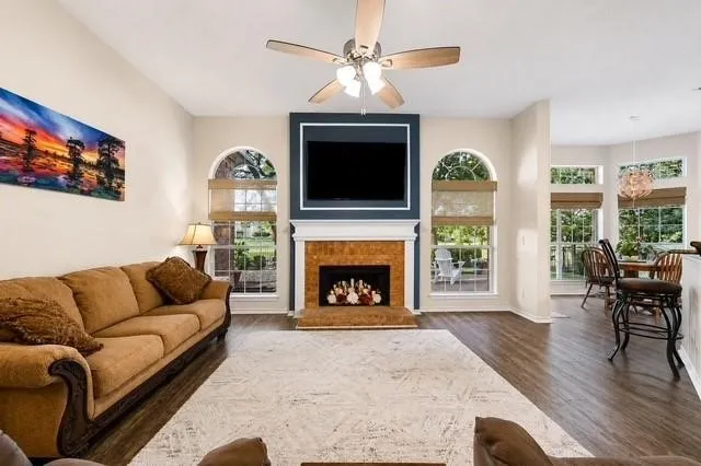 Spacious great room featuring hardwood flooring, a gas fireplace with wood-finish surround, and a wall-mounted flat-screen television