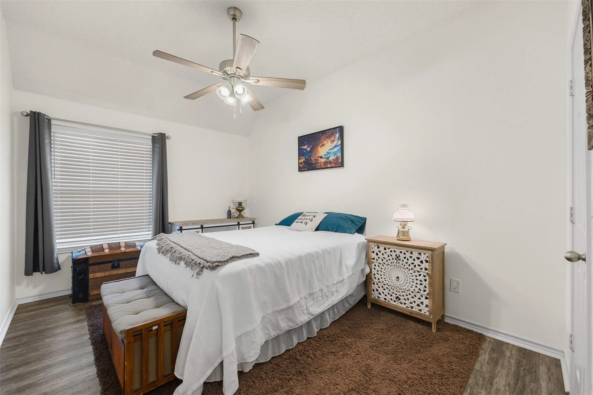 Vaulted ceiling with a ceiling fan, wood-finish flooring, and white walls