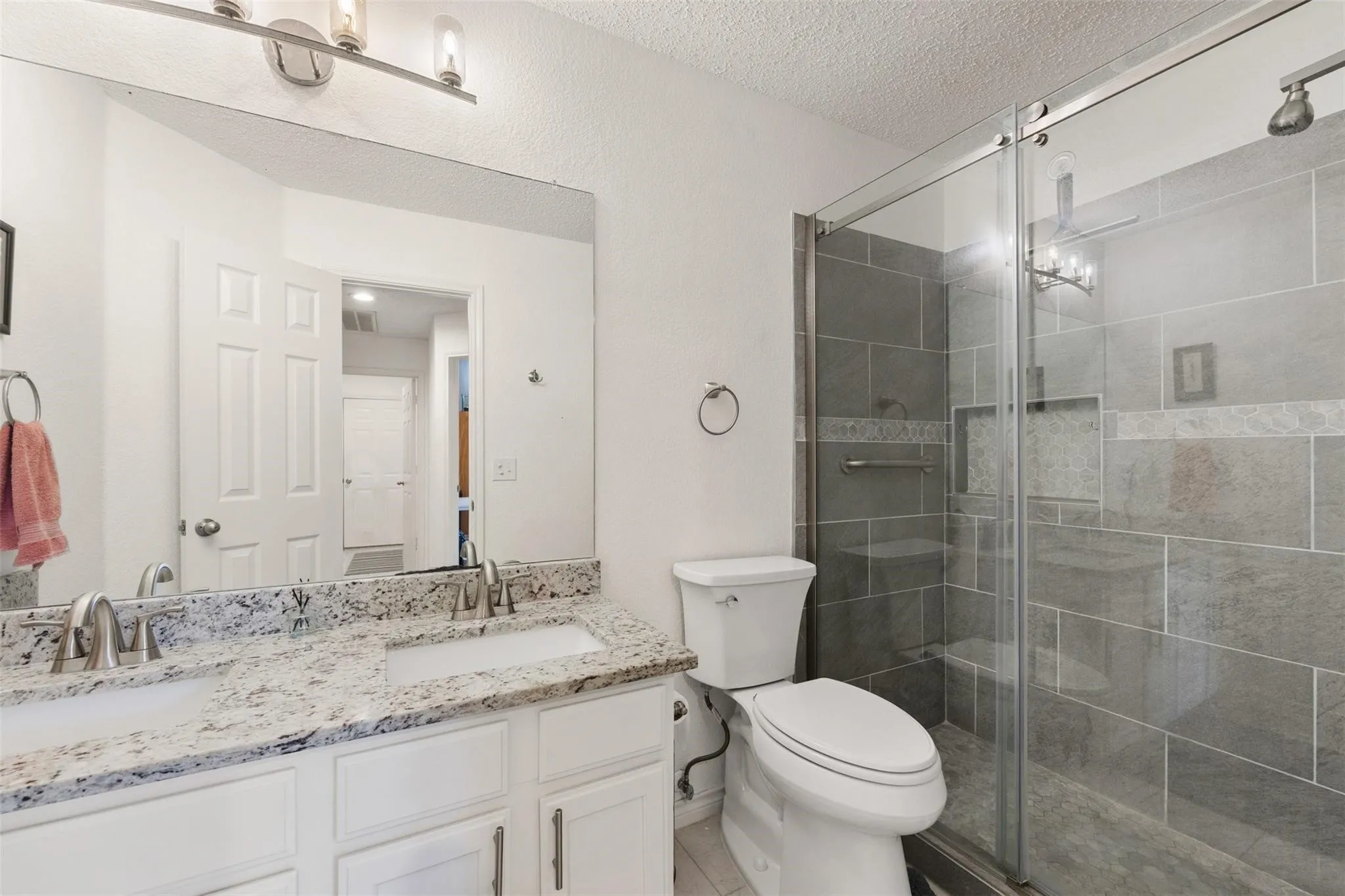 Dual vanity with stone-finish countertop, white cabinetry, and undermount sinks