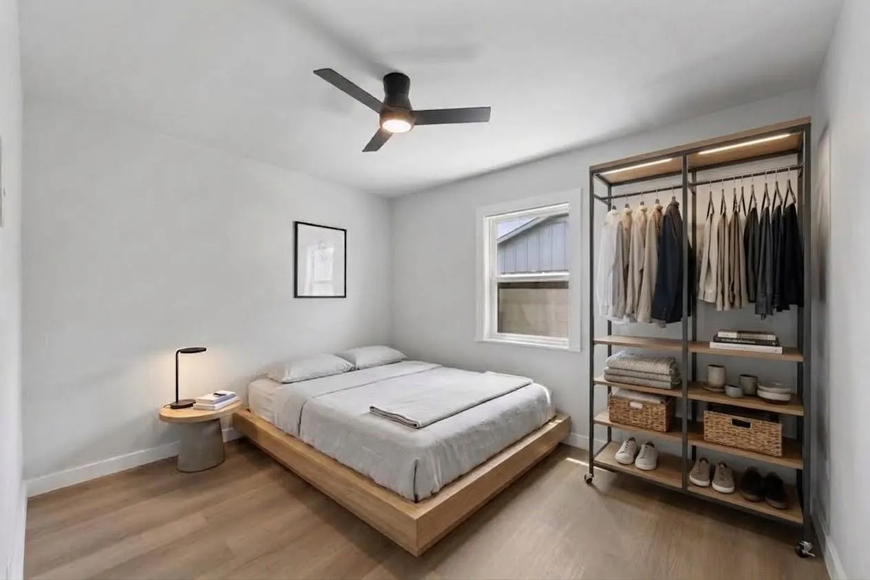 Light wood-finish flooring, white walls, and a modern ceiling fan with integrated lighting