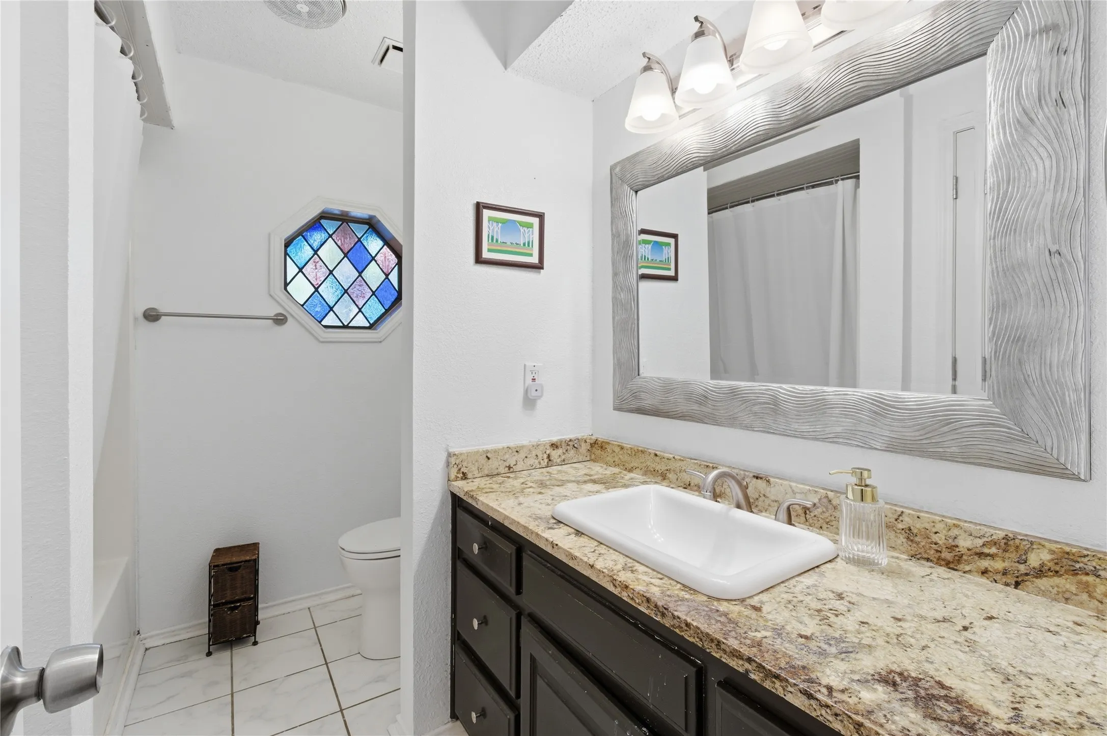 Vanity with an integrated rectangular sink, stone-finish countertop, and dark wood-finish cabinetry