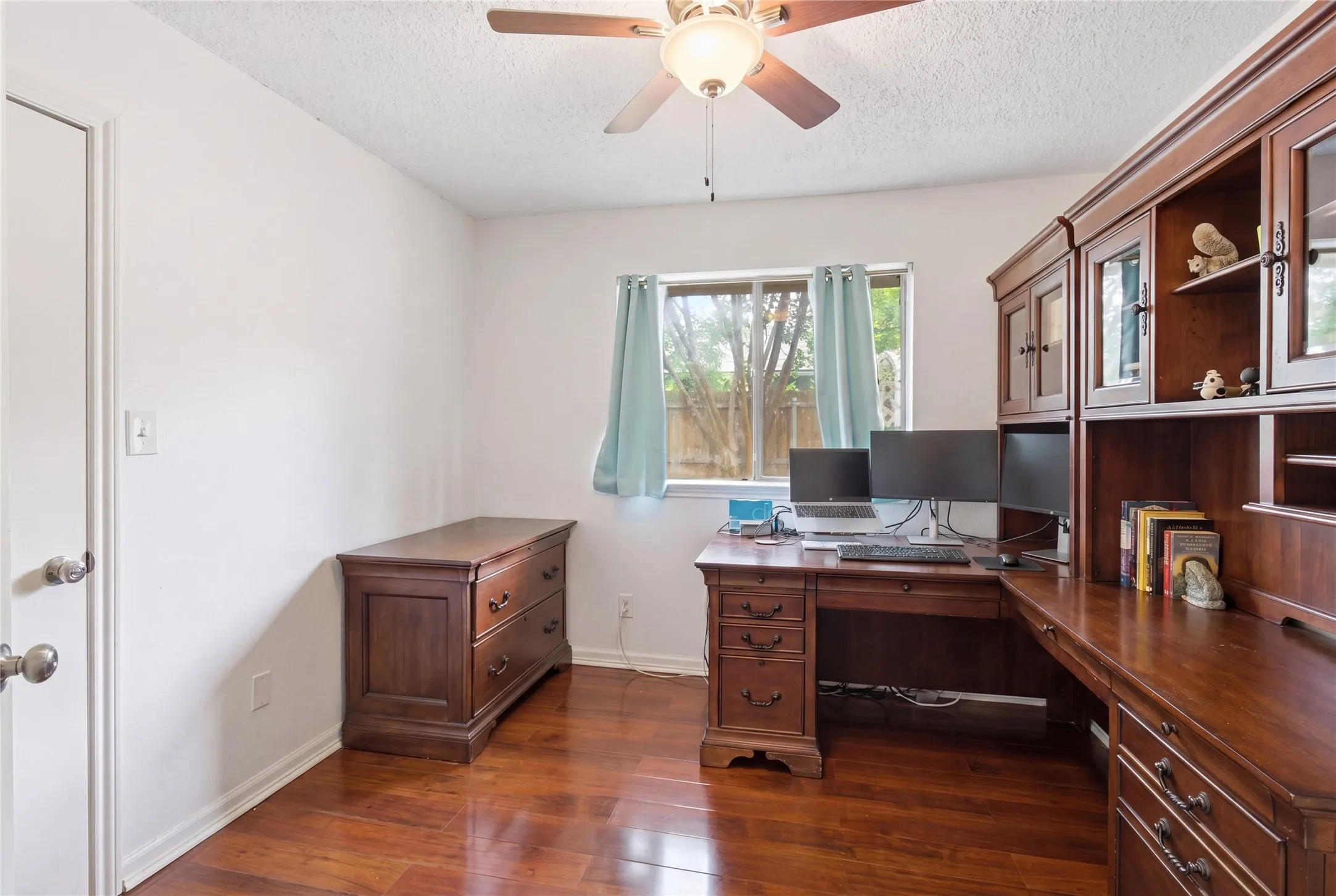 Wood-finish flooring, ceiling fan with integrated lighting, and a window with natural light