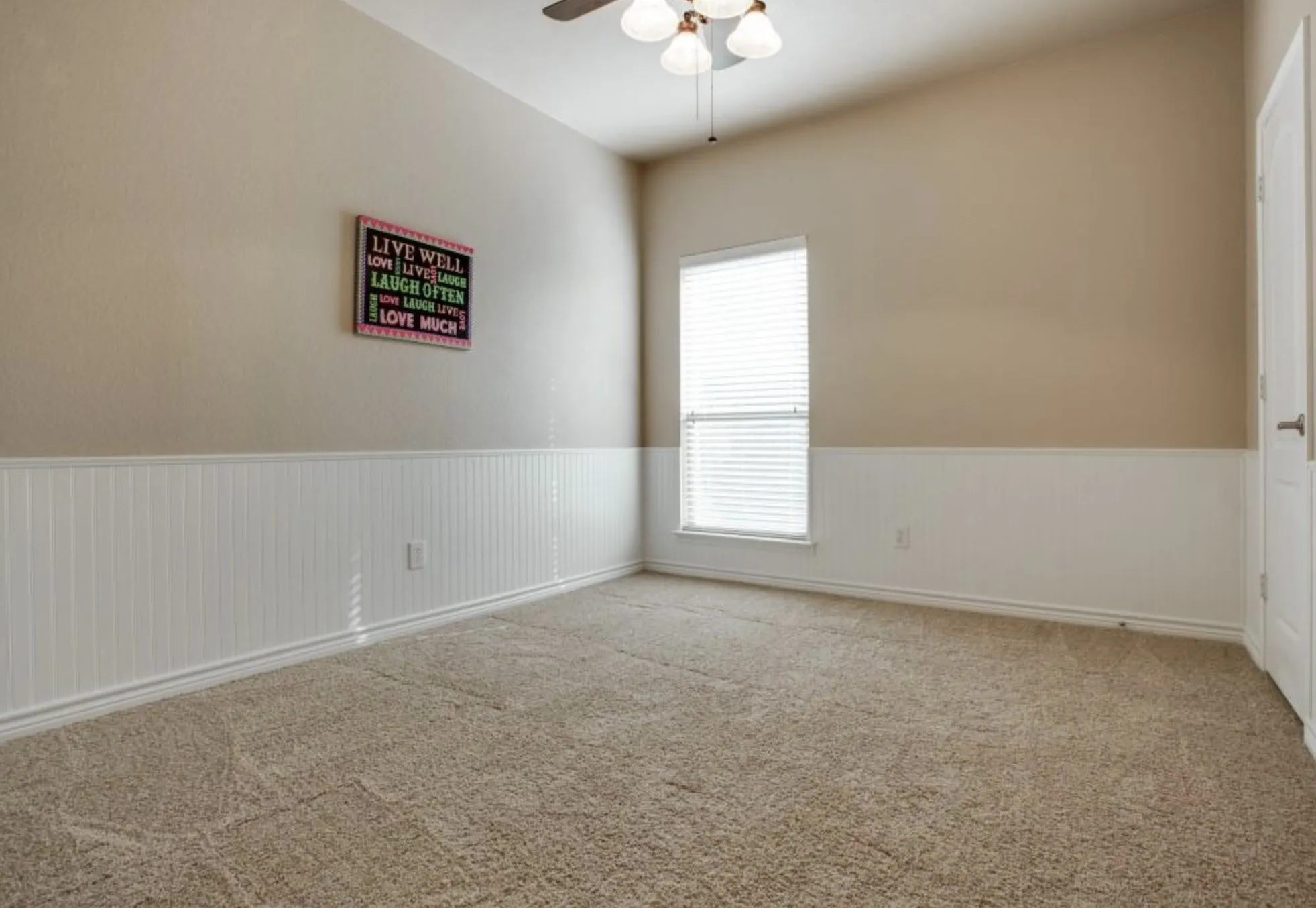 Carpeted flooring, vaulted ceiling, beadboard wainscoting, window with blinds, and ceiling fan with light fixture