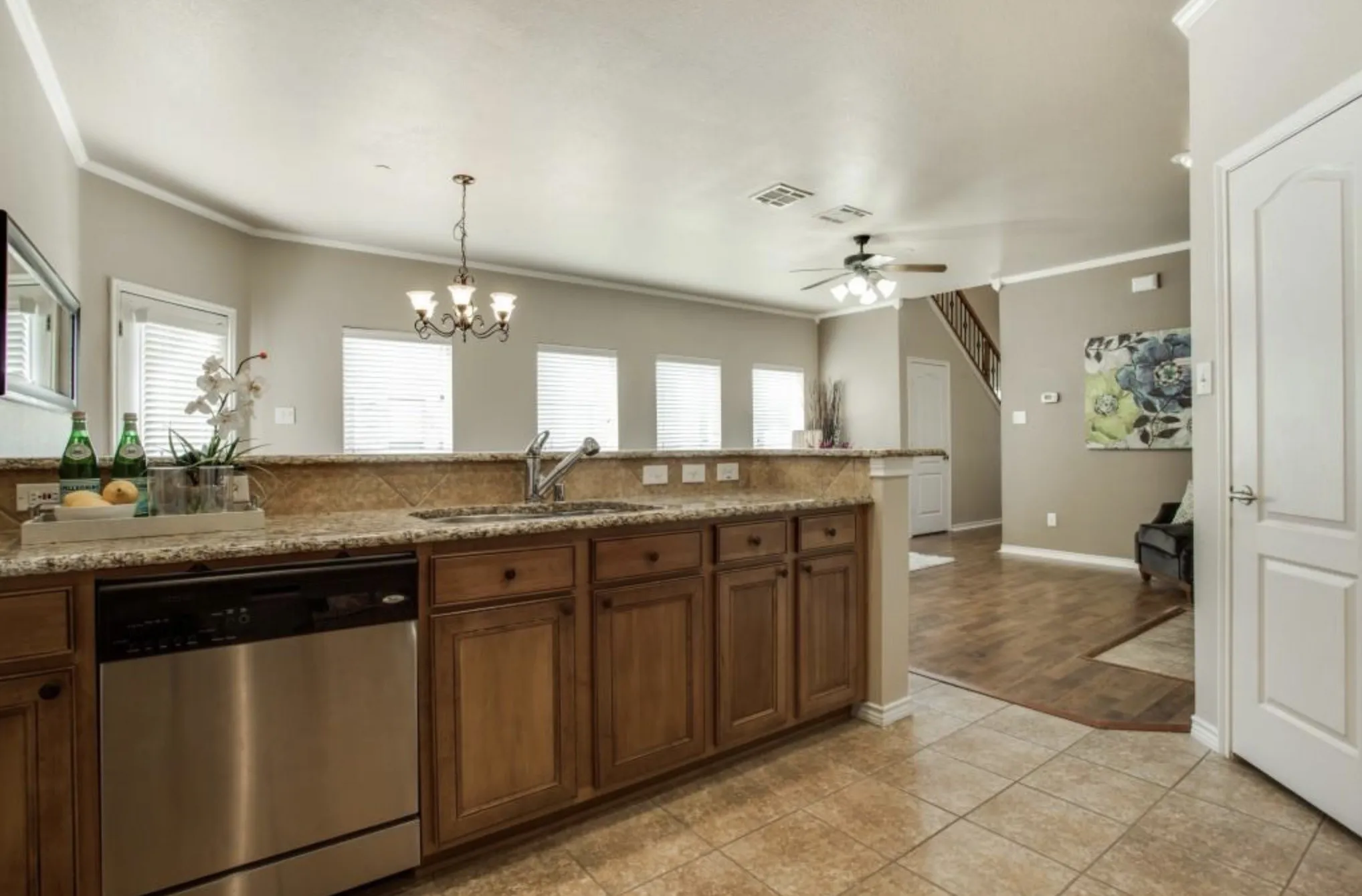 Kitchen featuring warm wood cabinetry, granite countertops, stainless steel dishwasher, and tile flooring