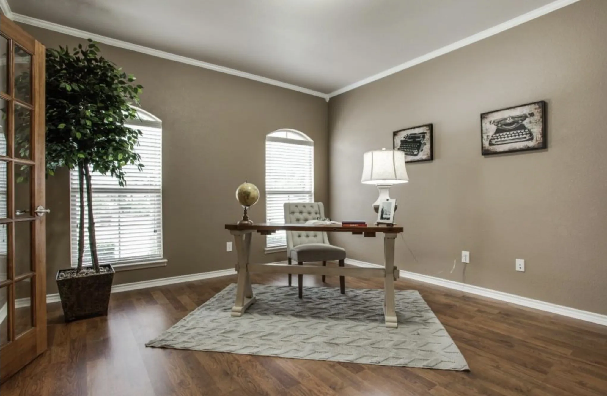 Wood-finish flooring, arched windows with blinds, and a paneled glass door