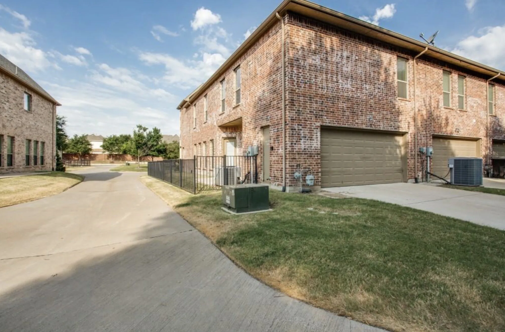 Brick exterior featuring multiple windows, an attached garage, and a concrete driveway