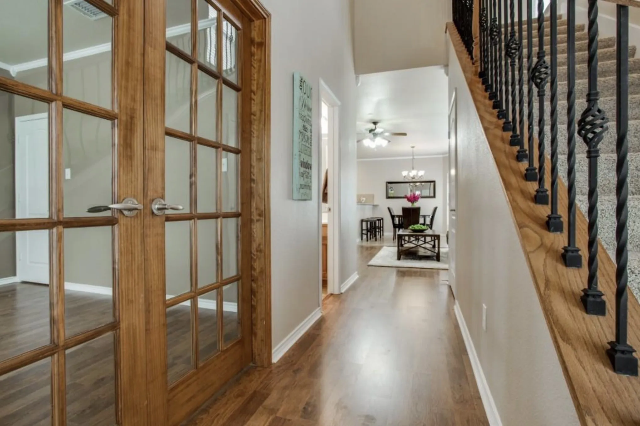 Wood-finish flooring throughout, with a carpeted staircase featuring wrought iron balusters