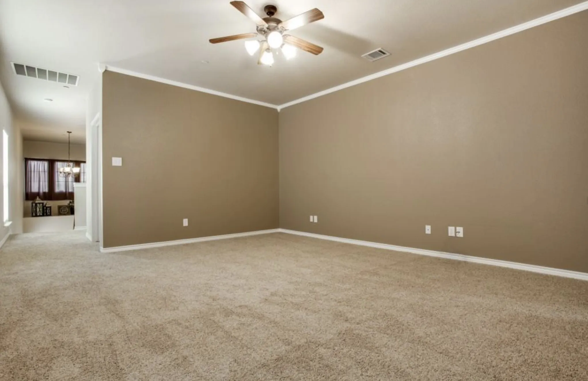 Spacious room with plush carpeting, neutral wall color, white crown molding, and a ceiling fan with integrated lighting