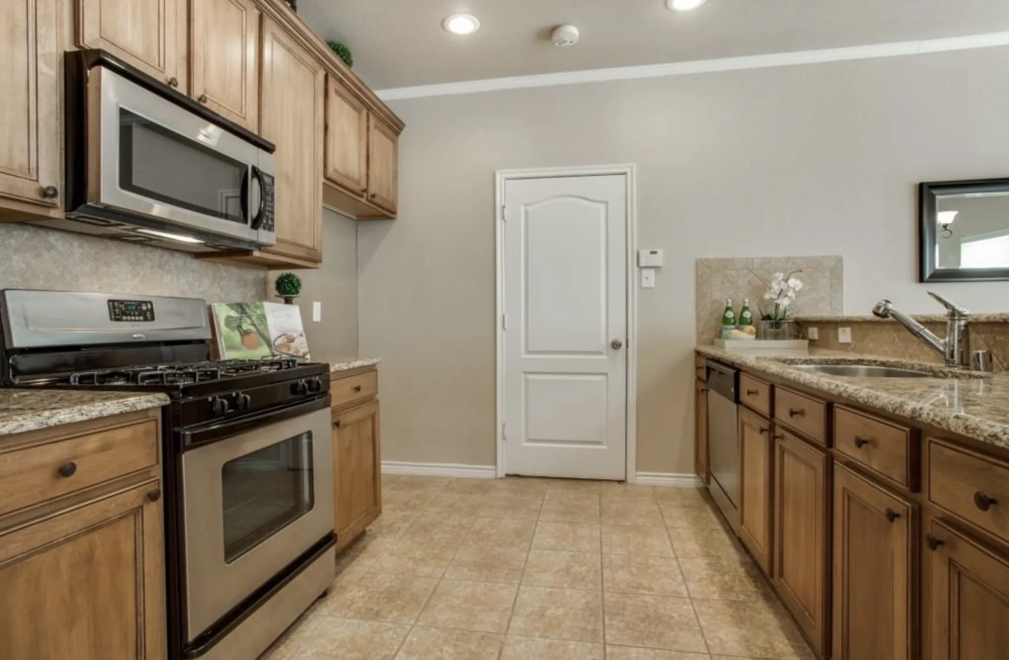 Kitchen featuring wood cabinetry, stainless steel appliances, speckled countertops, and a tile floor
