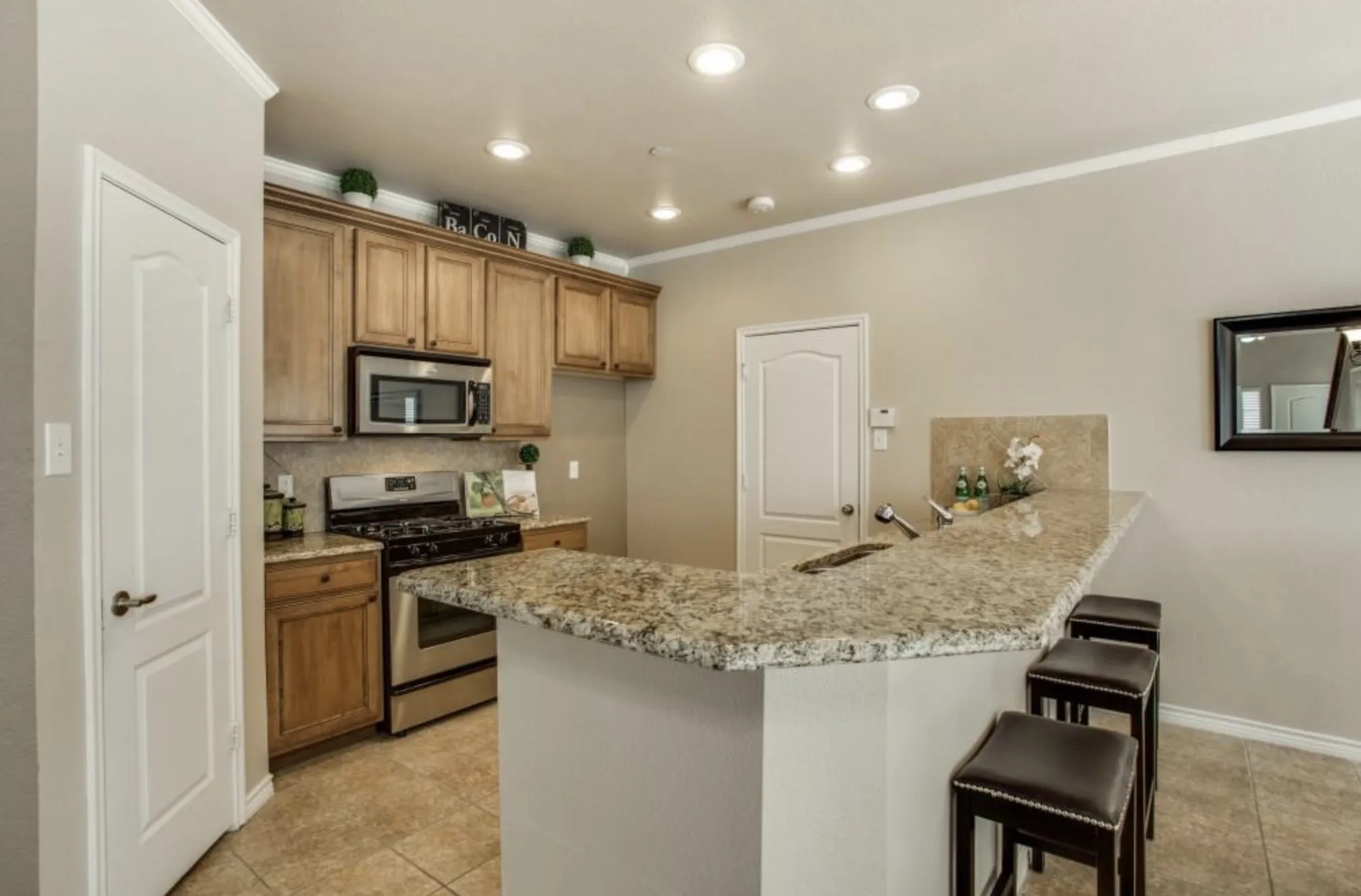 Kitchen featuring wood cabinetry, stainless steel appliances, a multi-level breakfast bar, recessed lighting, and tile flooring