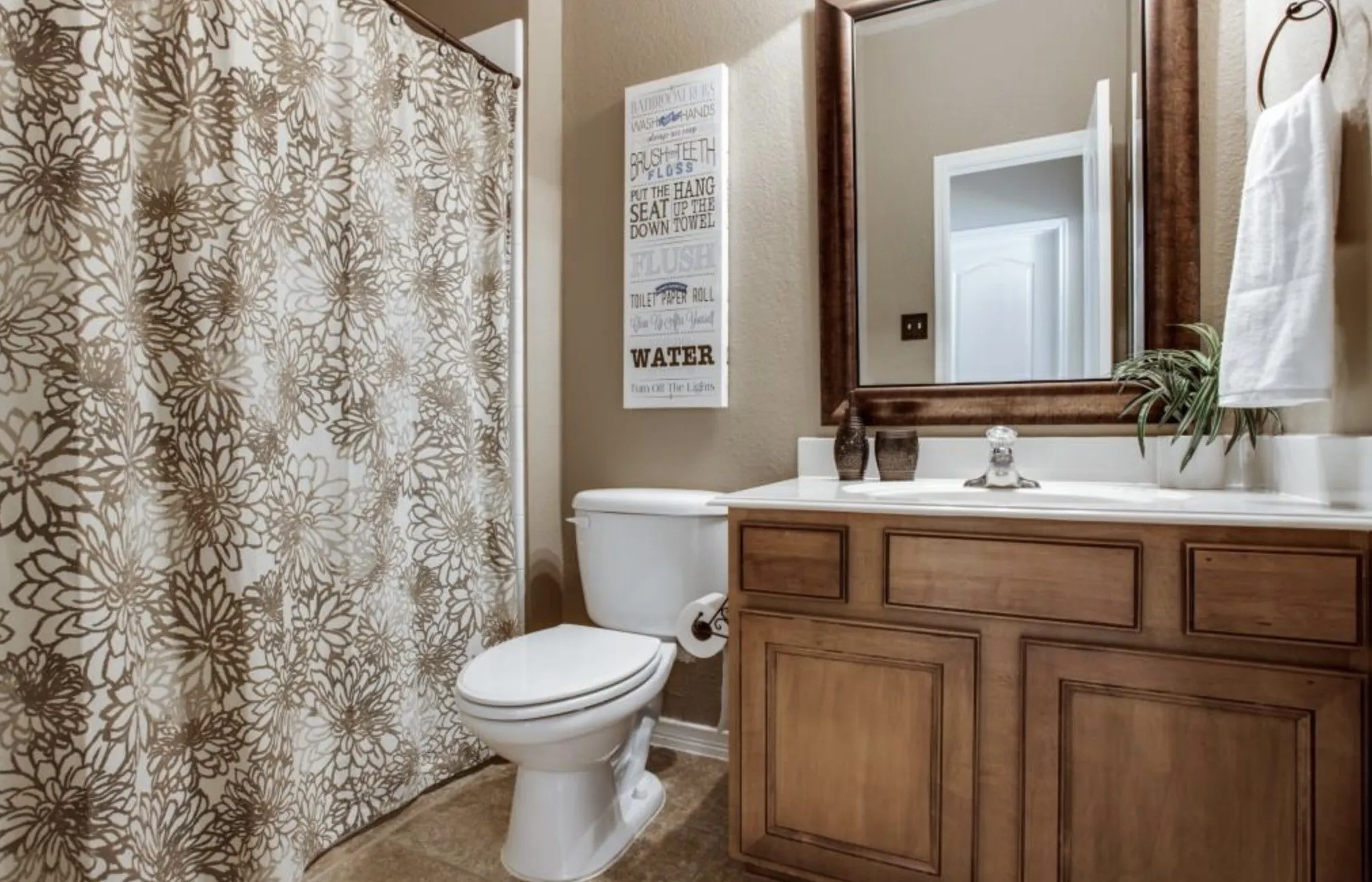White vanity countertop, wood-finish cabinetry, framed mirror, and built-in toilet
