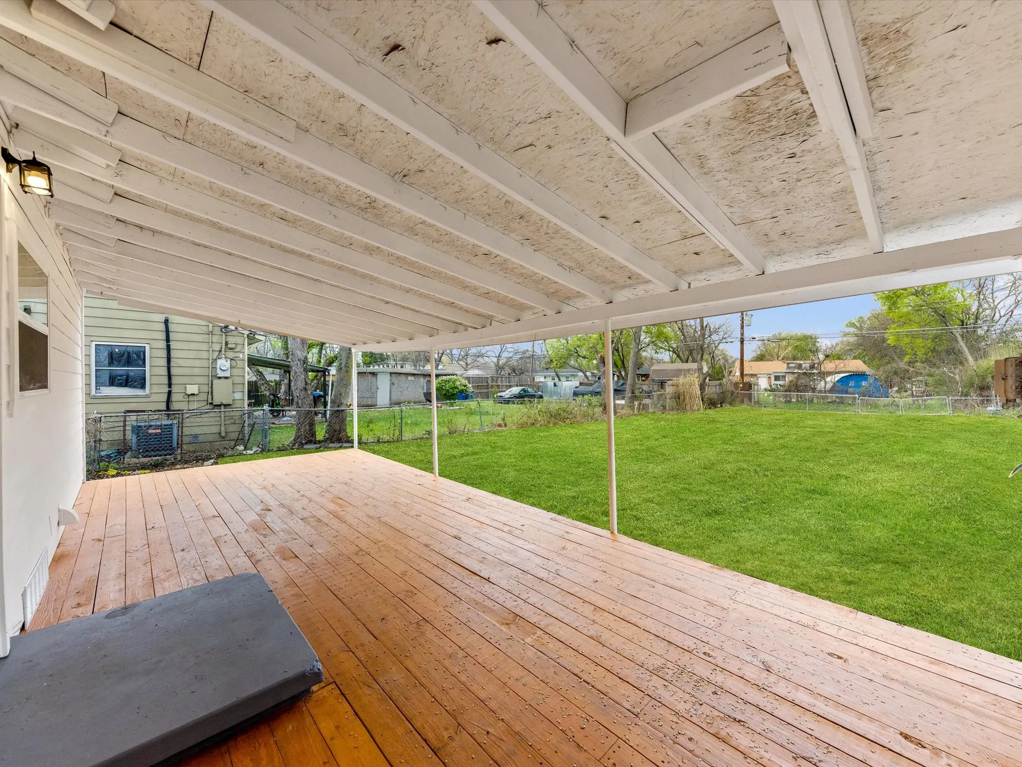 Expansive wood-finish deck with a large covered patio structure and outdoor lighting