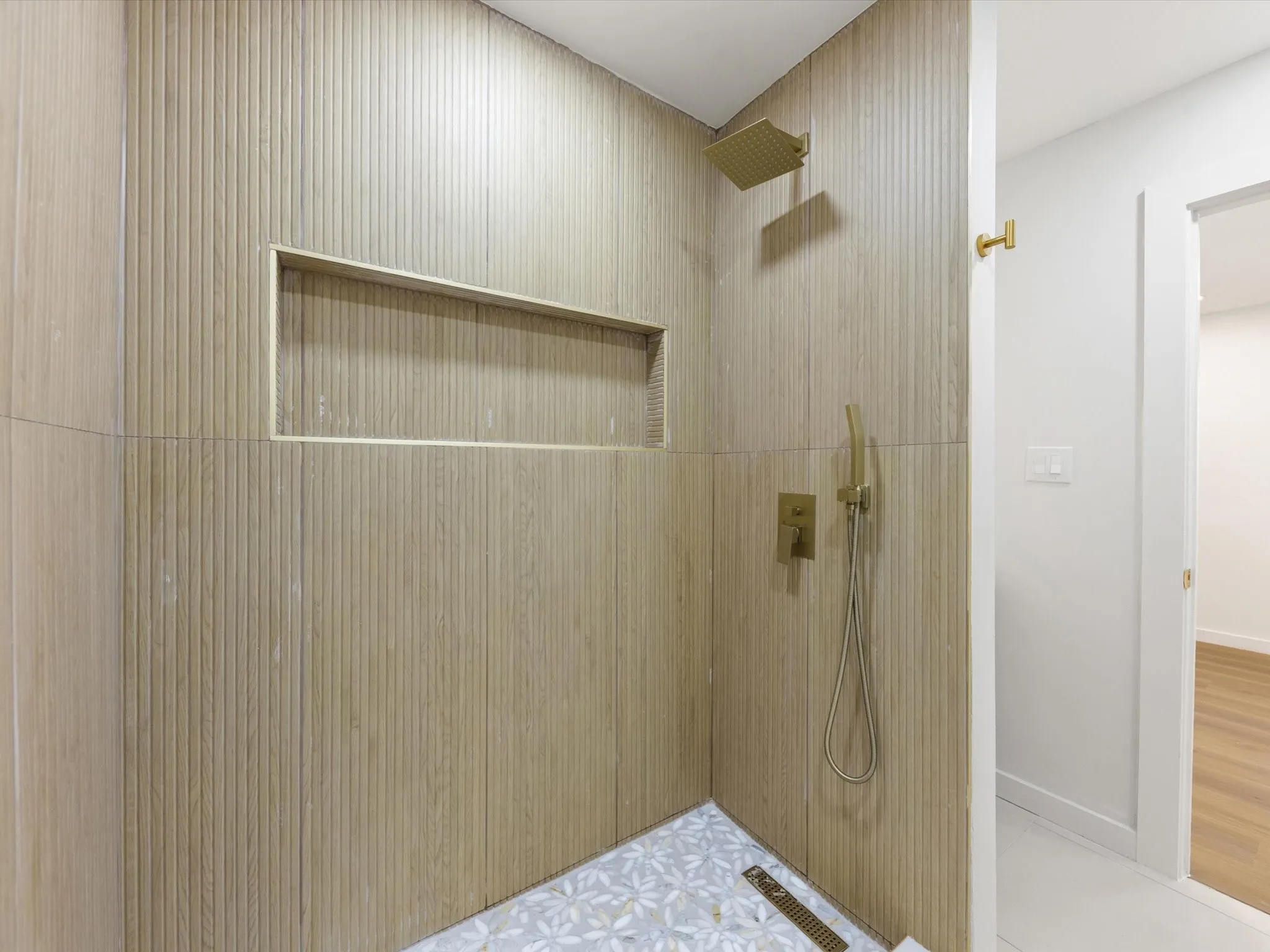Shower with textured tile walls, integrated niche, rain shower head, and handheld sprayer