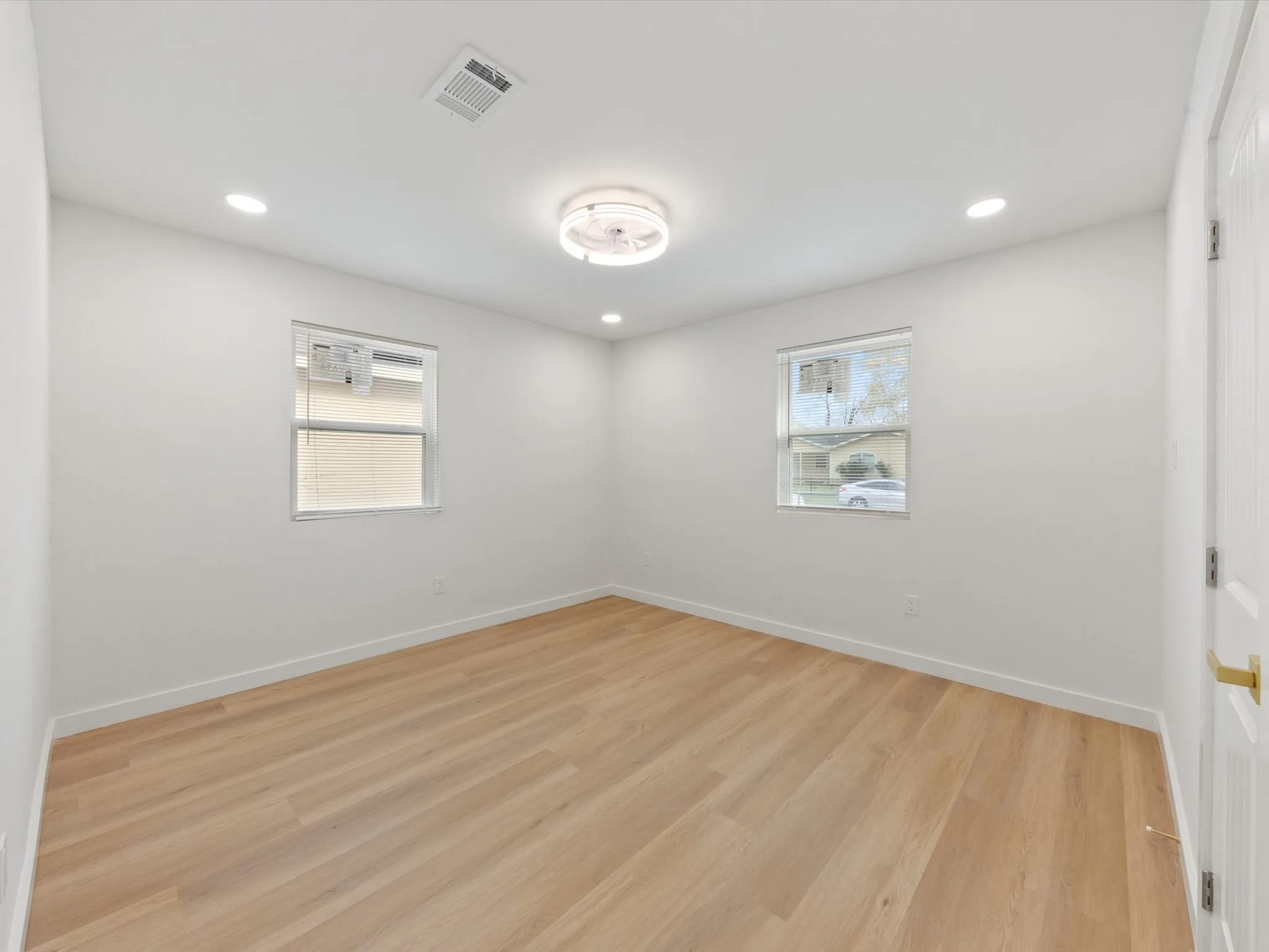 Light wood-finish flooring, recessed lighting, and a contemporary flush-mount ceiling fixture