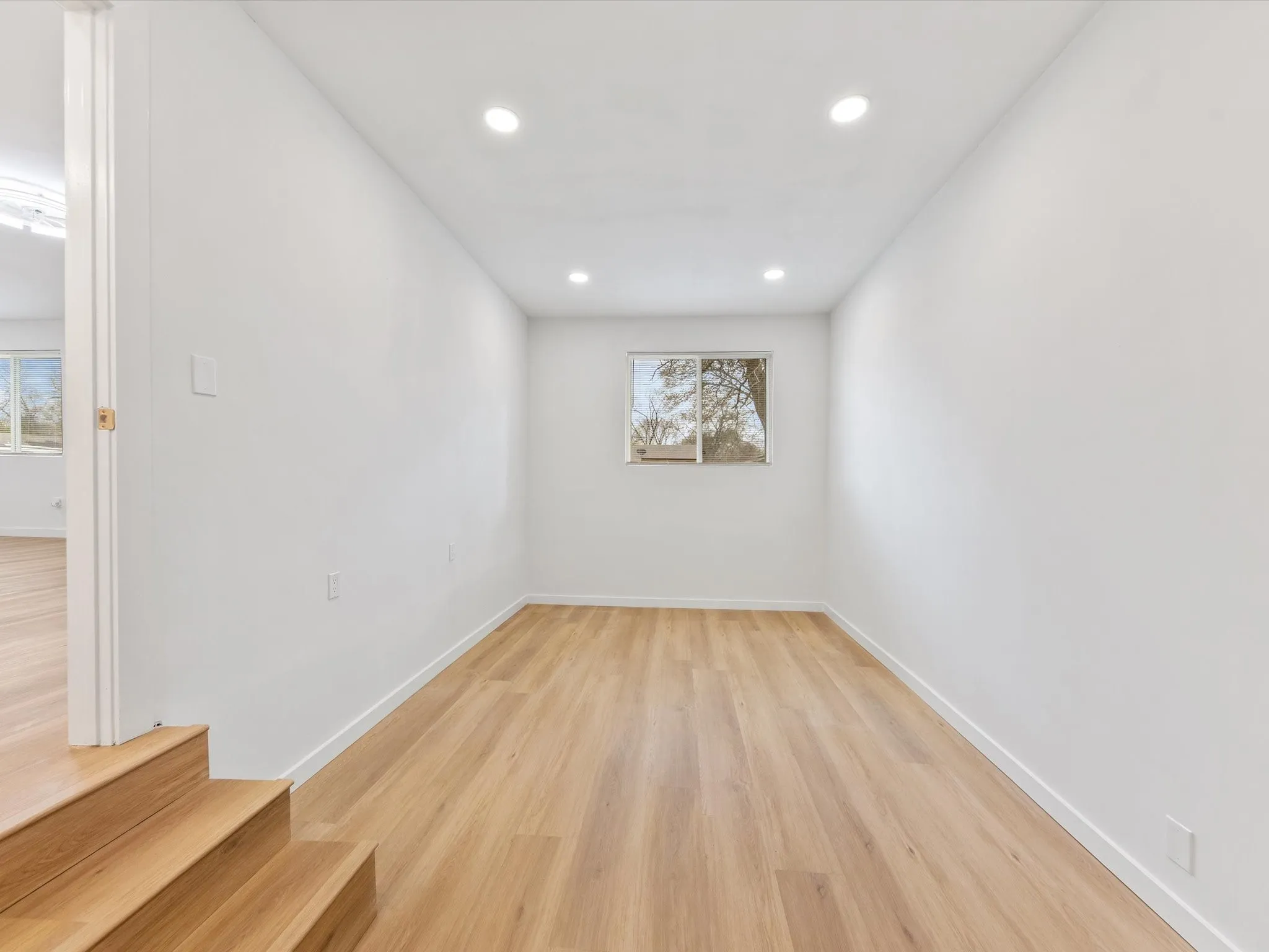 Recessed lighting, wood-finish flooring, and a window with a white frame