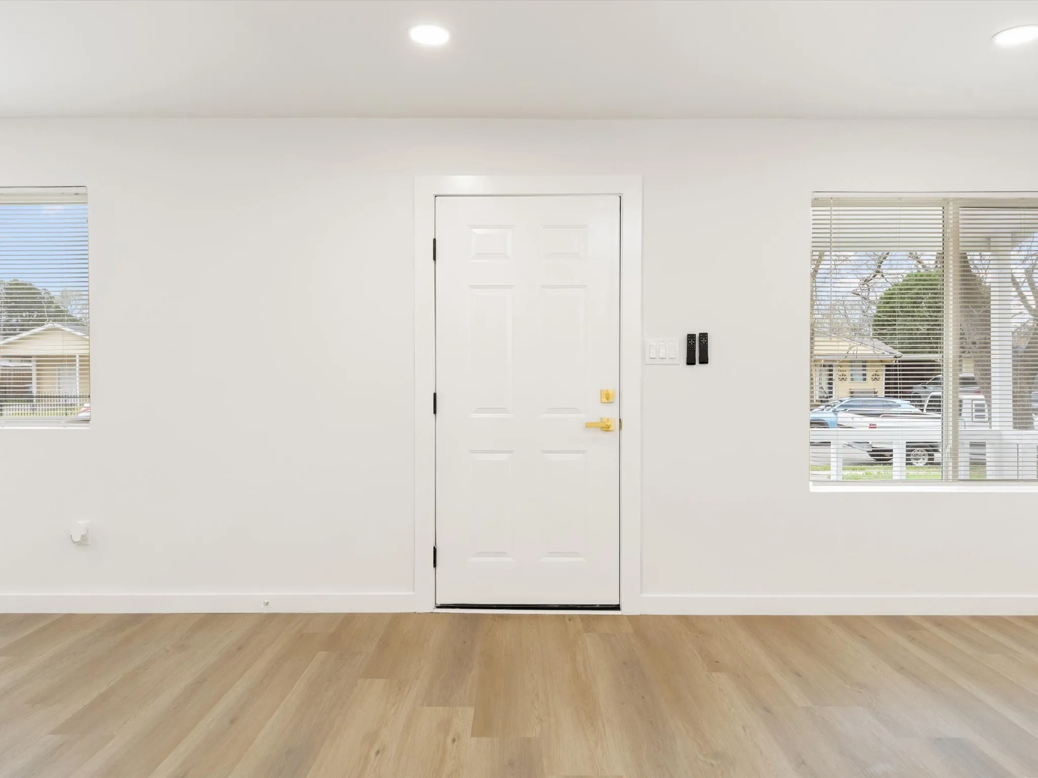 Recessed lighting, wood-finish flooring, white paneled door, and dual windows