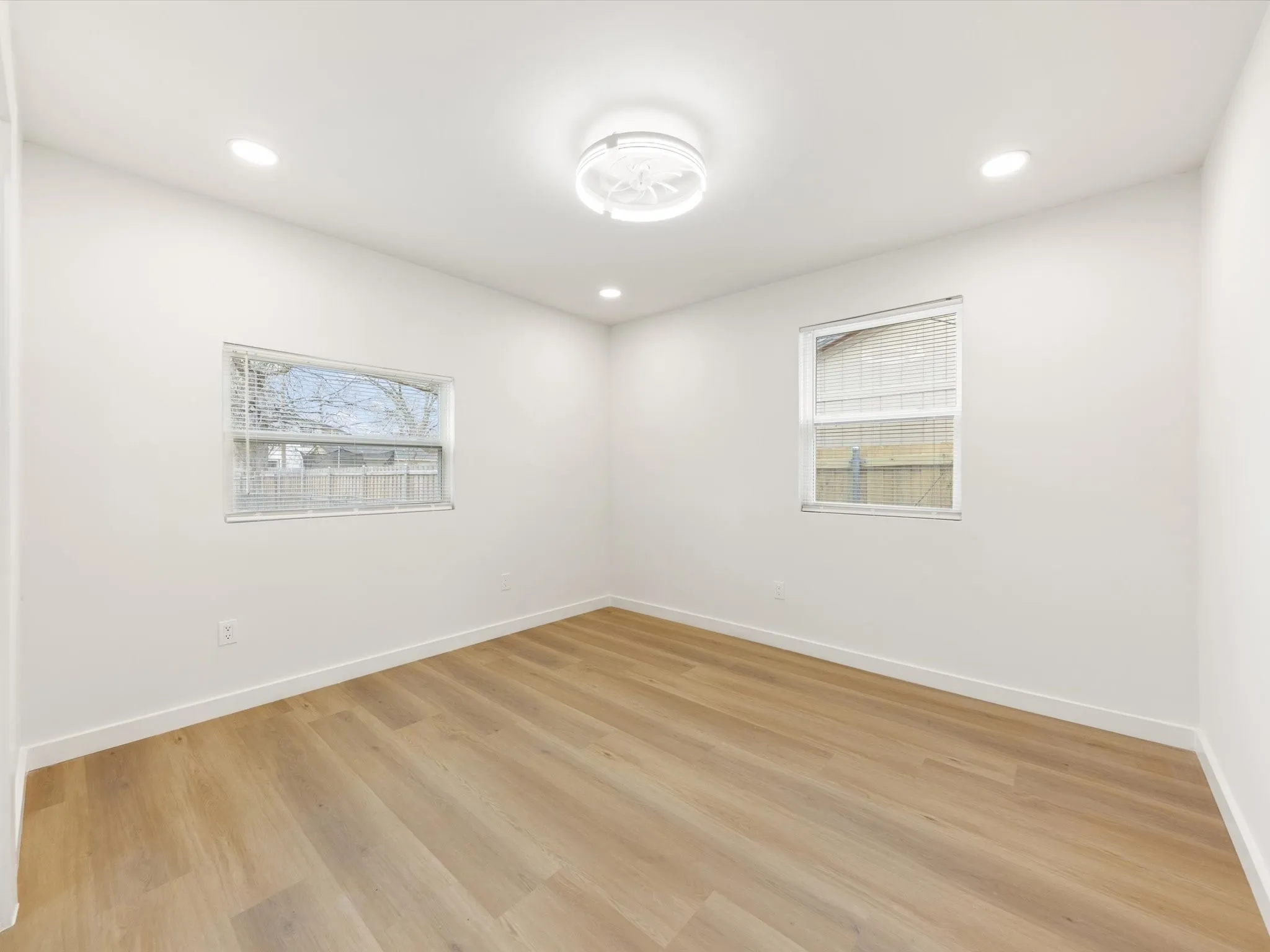 Neutral white walls with wood-finish flooring, recessed lighting, and a contemporary ceiling fixture