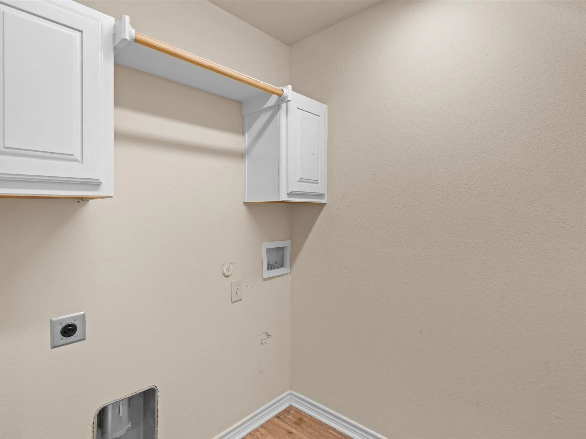 White cabinetry, wood-finish flooring, and a built-in hanging rod