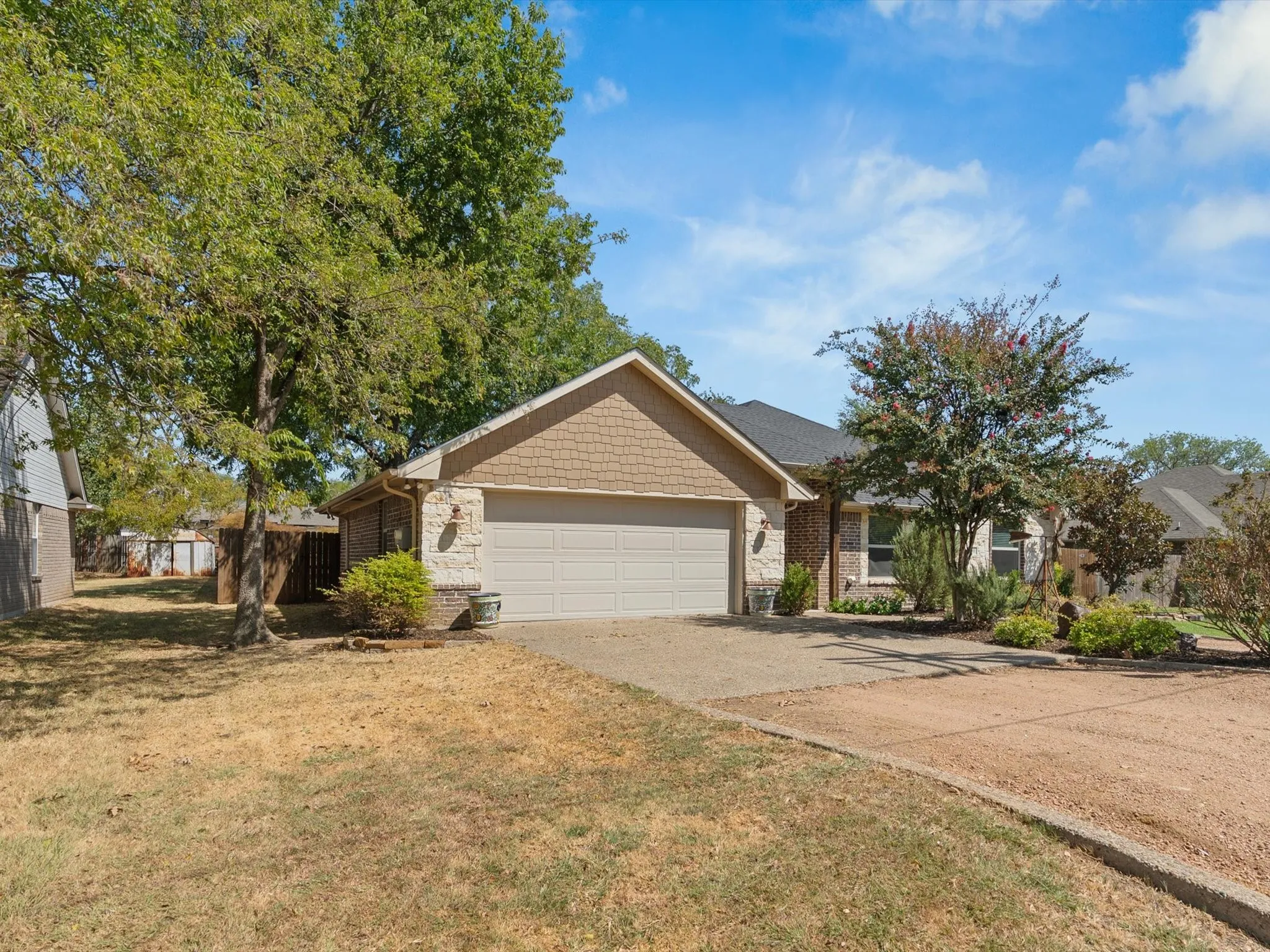 Brick and stone exterior with shake siding accents, an attached two-car garage, and a concrete driveway