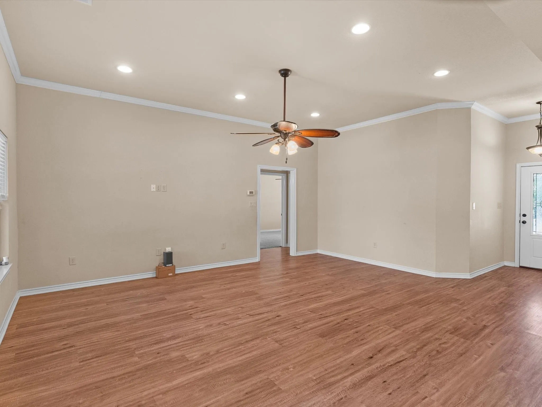 Spacious room featuring wood-finish flooring, recessed lighting, and crown molding