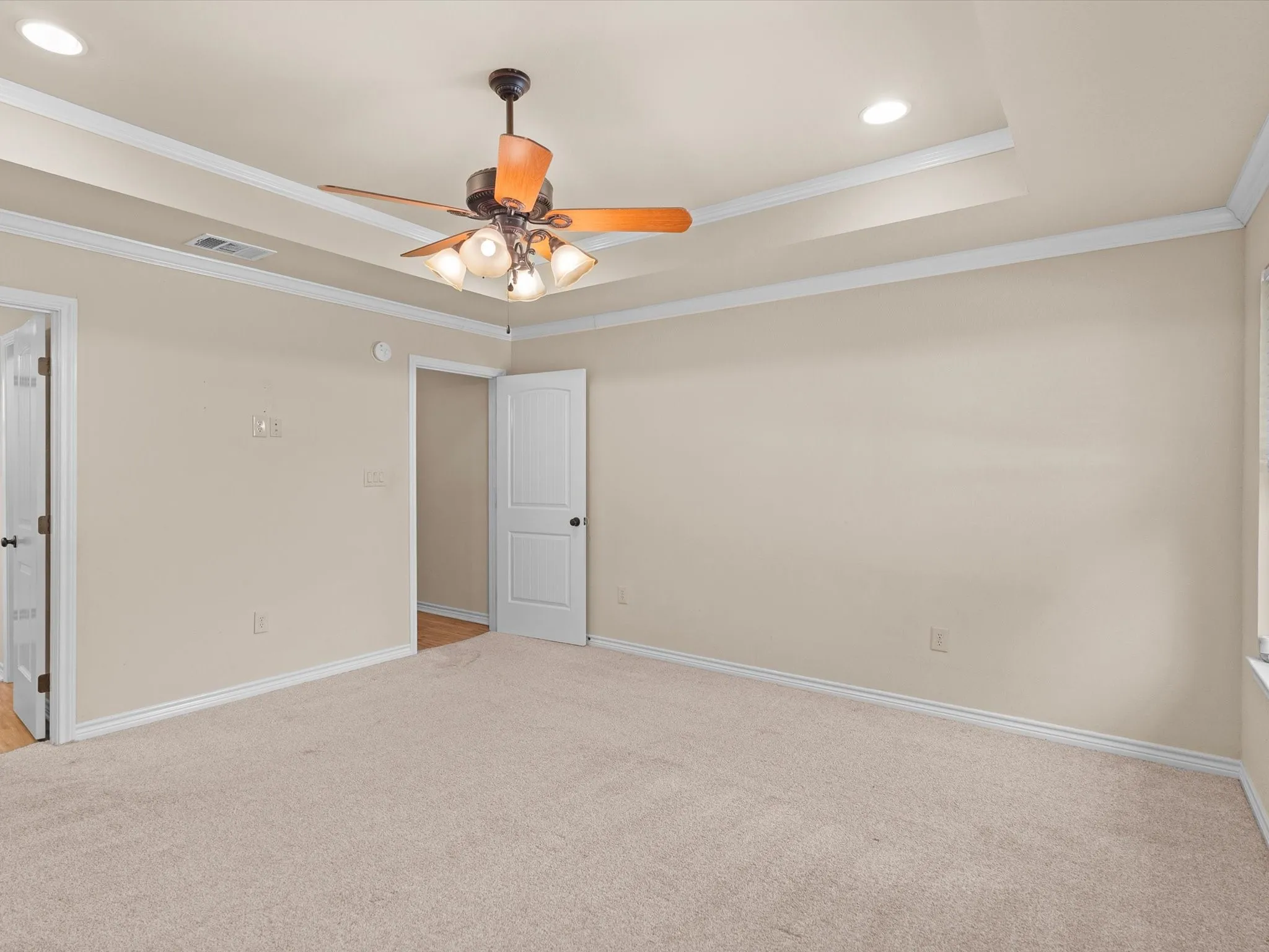 Tray ceiling with recessed lighting and a ceiling fan, neutral wall paint, and light-toned carpeting