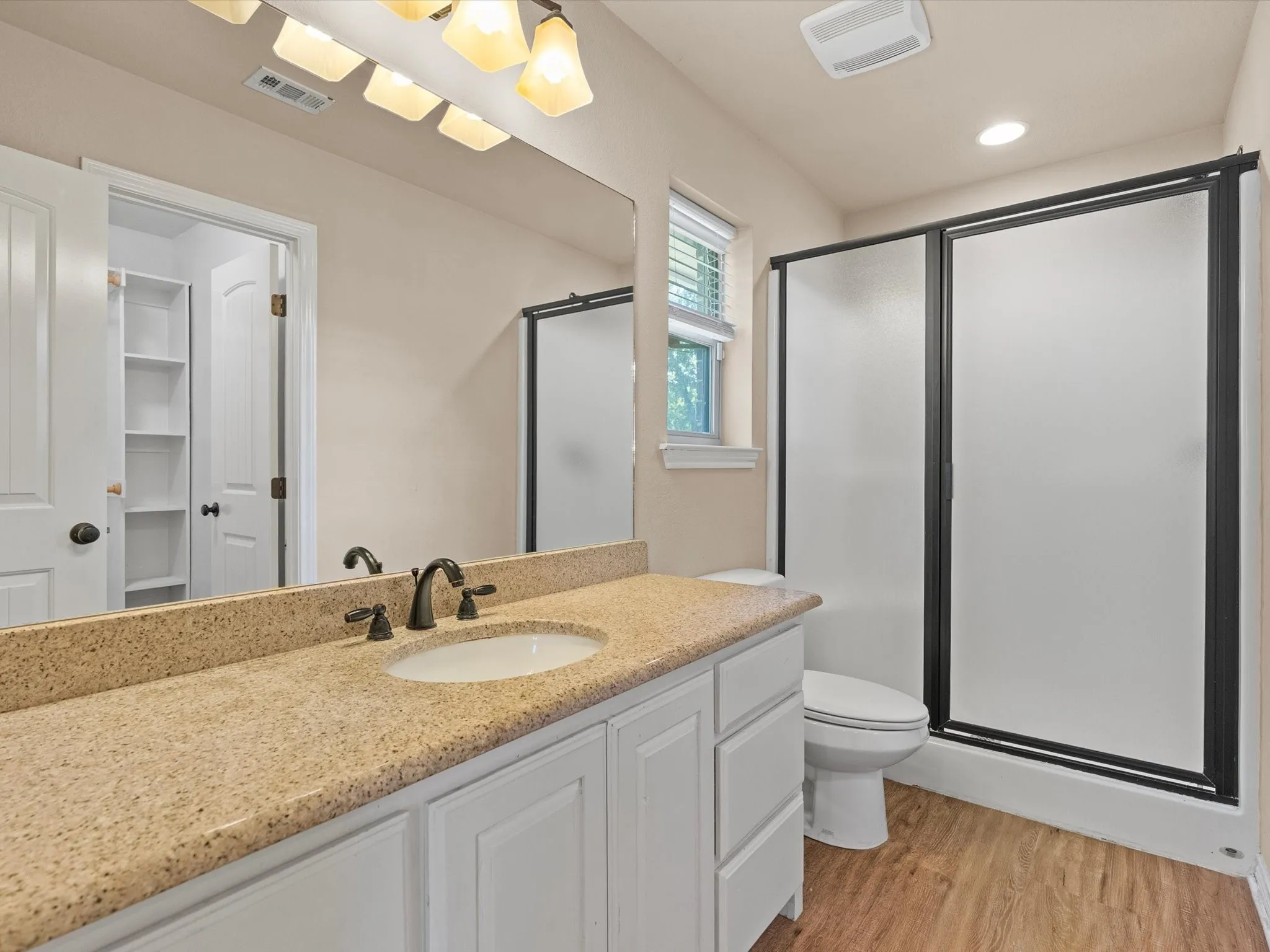 White vanity with a stone-finish countertop, undermount sink, and dark-finish faucet