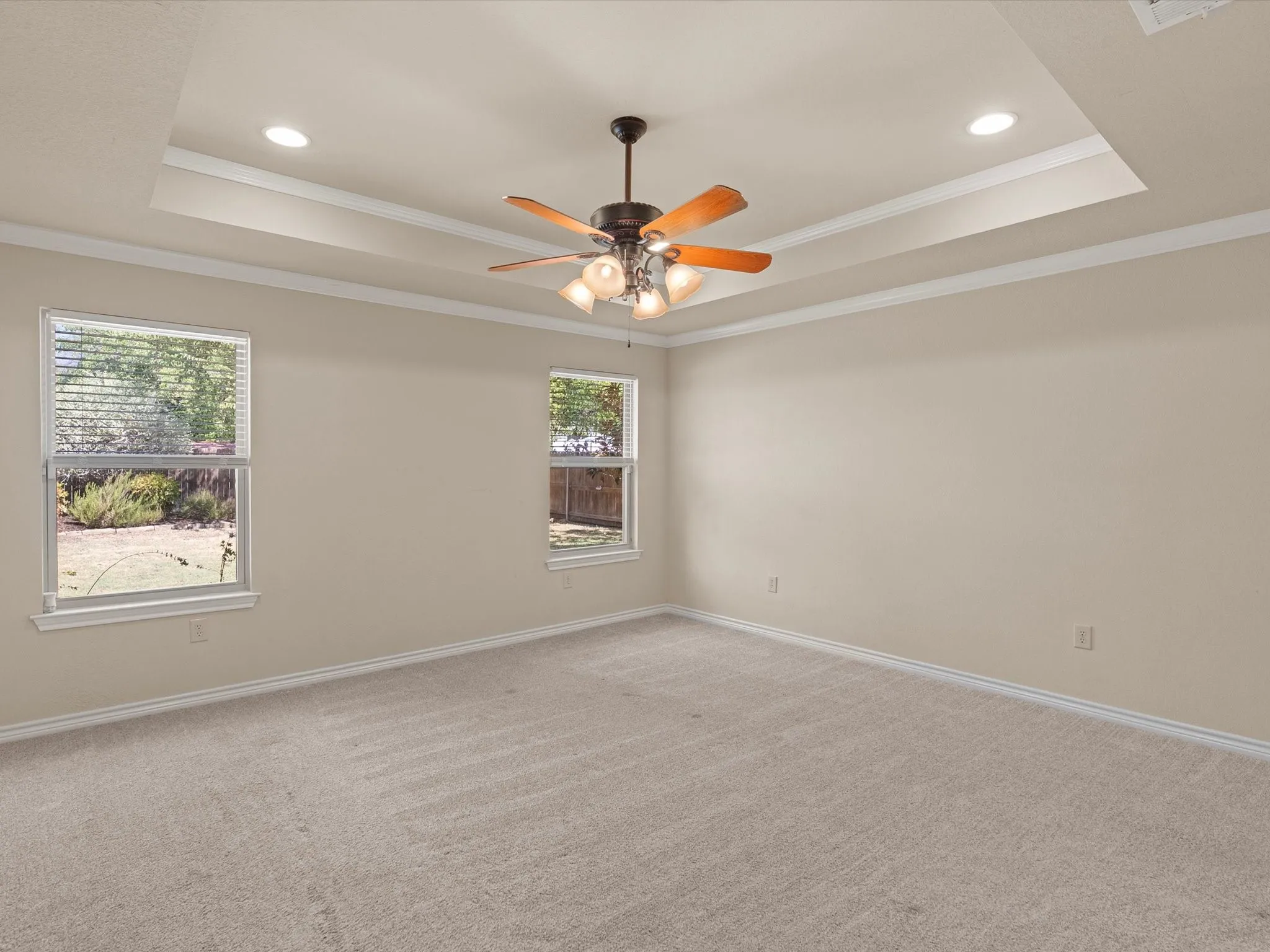 Tray ceiling with crown molding, recessed lighting, ceiling fan with light fixture, neutral wall color, and carpet flooring