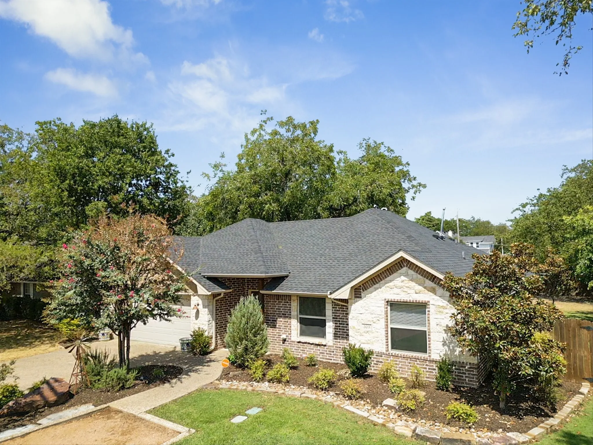 Brick and stone veneer exterior with a dark shingle roof