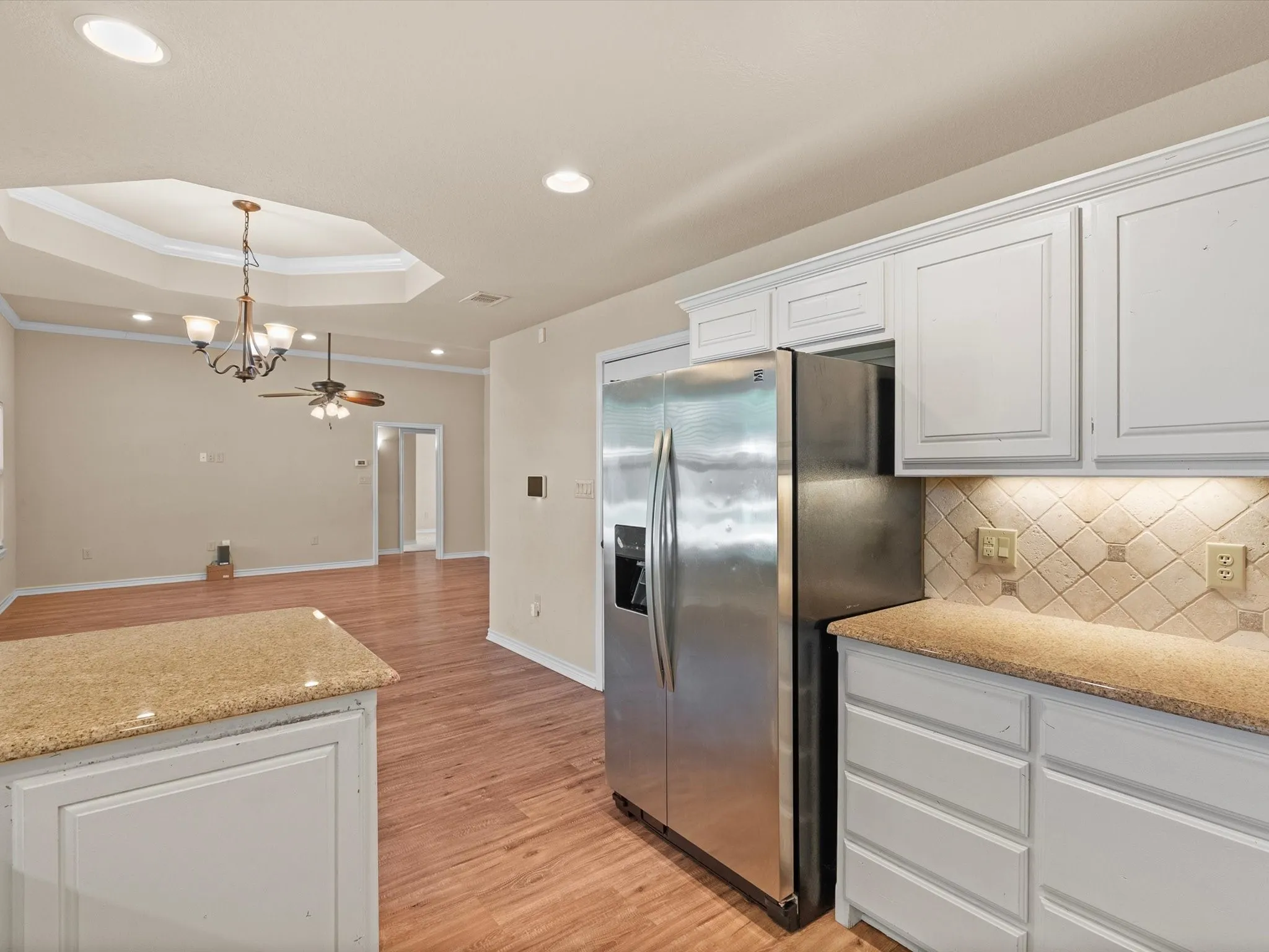 Kitchen featuring white cabinetry with crown molding, light-colored countertops, and a tiled backsplash