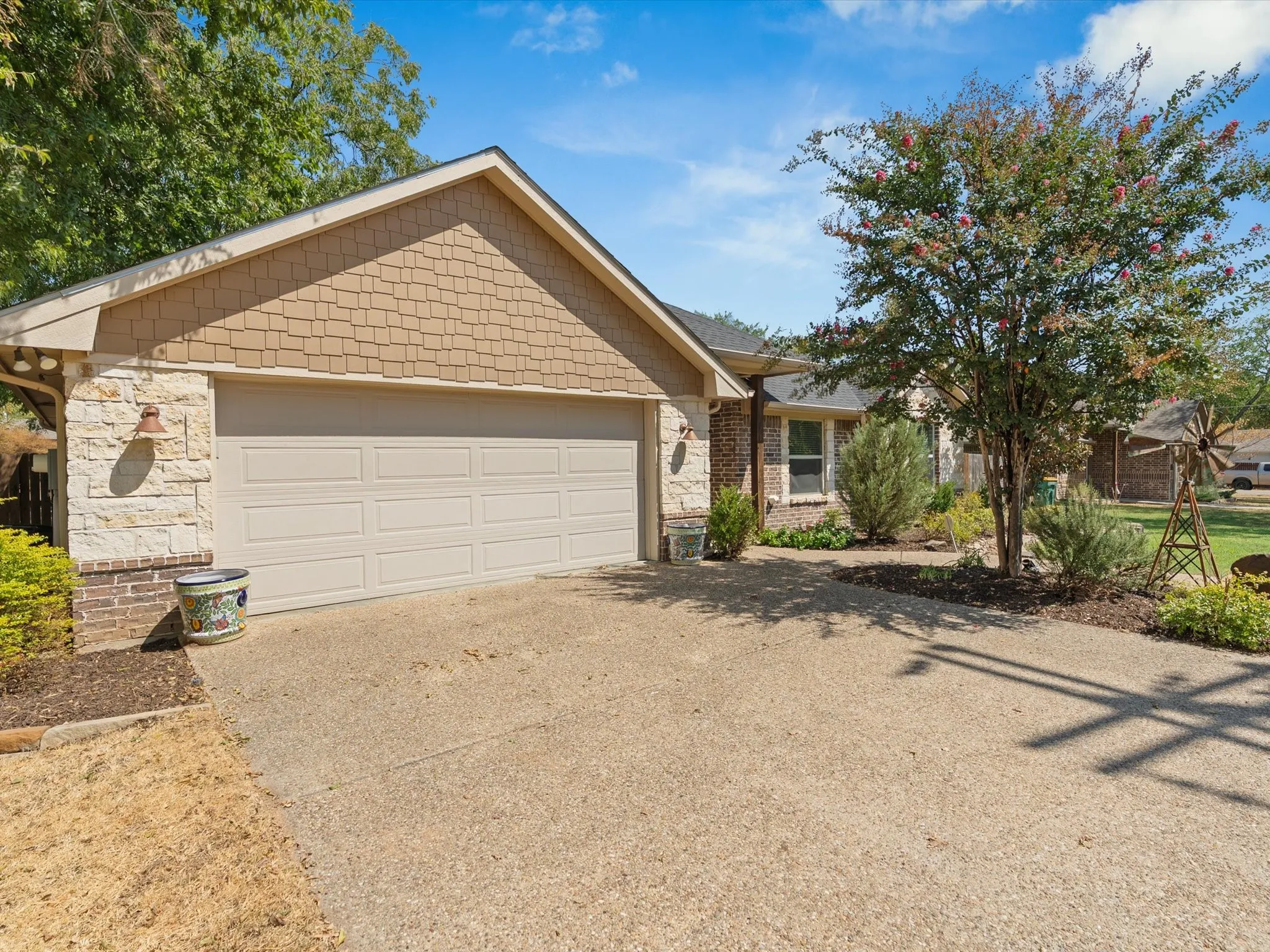 Attached two-car garage with segmental door, stone façade, brick accents, and wood shake siding