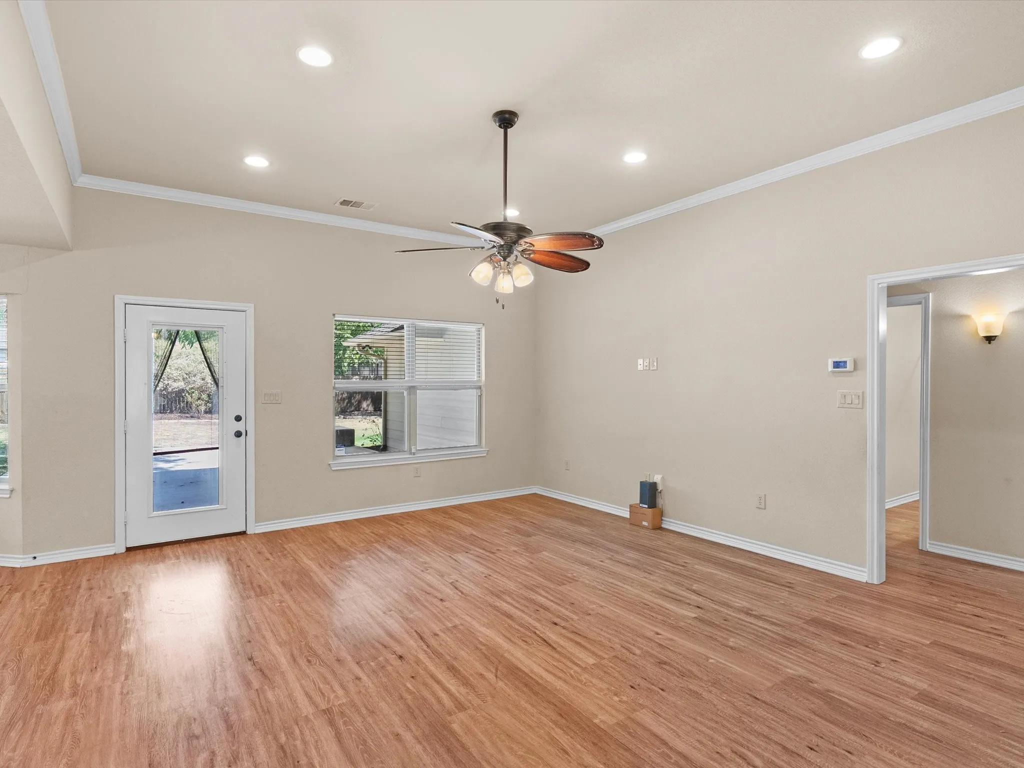 Vaulted ceiling, recessed lighting, wood-finish flooring, ceiling fan with light fixture, and an exterior glass-panel door