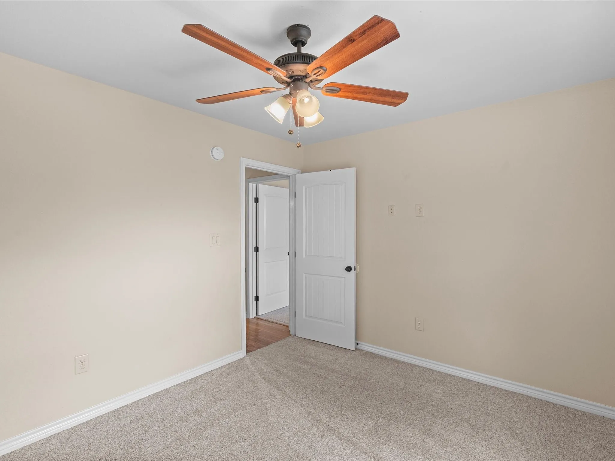 Wall-to-wall carpeting, overhead ceiling fan with light fixture, and paneled interior doors