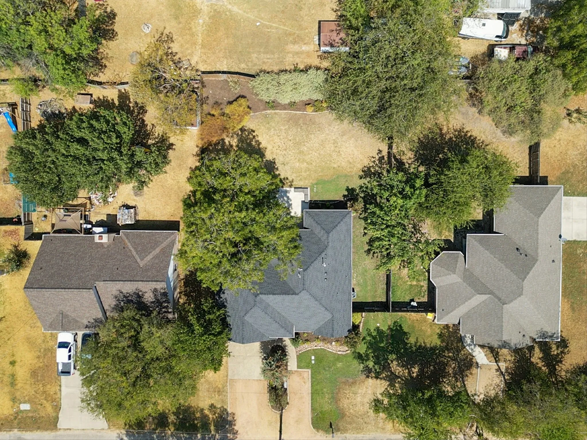 Pitched roofline residence with mature trees and a paved driveway