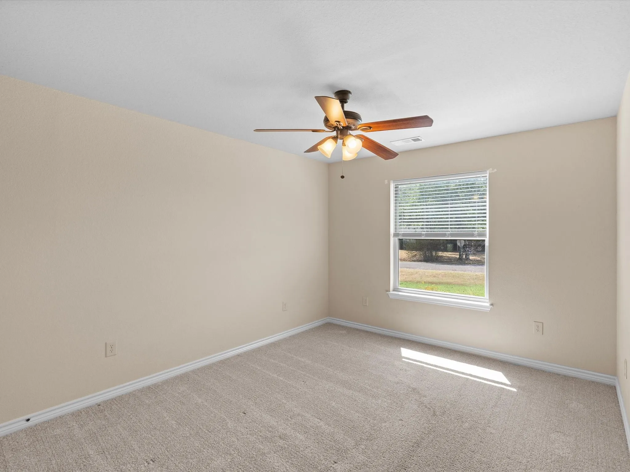 Carpeted flooring, neutral wall tones, ceiling fan with integrated lighting, and a window with horizontal blinds