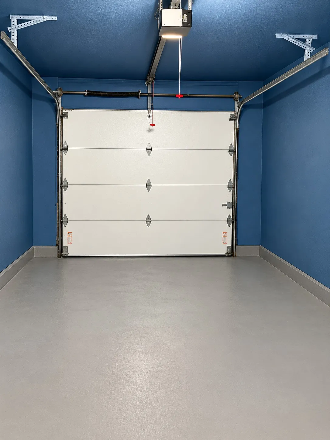 Garage with a light gray floor, blue walls and ceiling, and a white sectional garage door