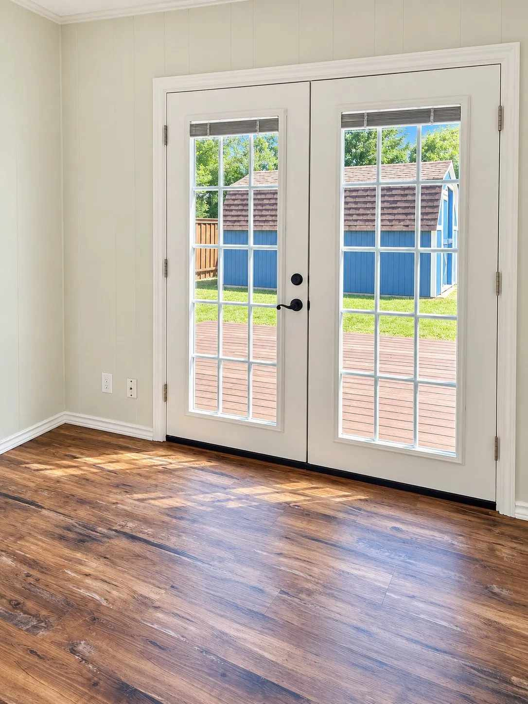 Wood-finish flooring, white trim, and double glass doors