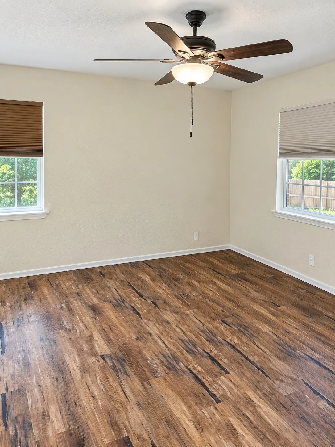 Wood-finish flooring, dual windows with blinds, and a ceiling fan with integrated lighting