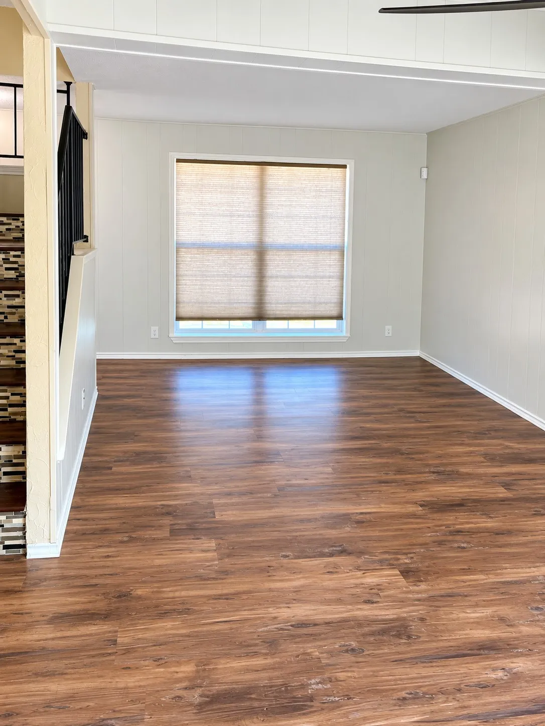 Recessed lighting, wood-finish flooring, and a large window with roller shades