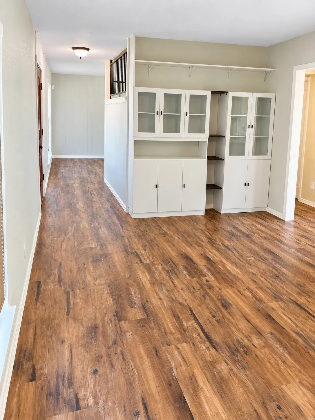 Wood-finish flooring throughout, complemented by built-in white cabinetry with glass-front doors