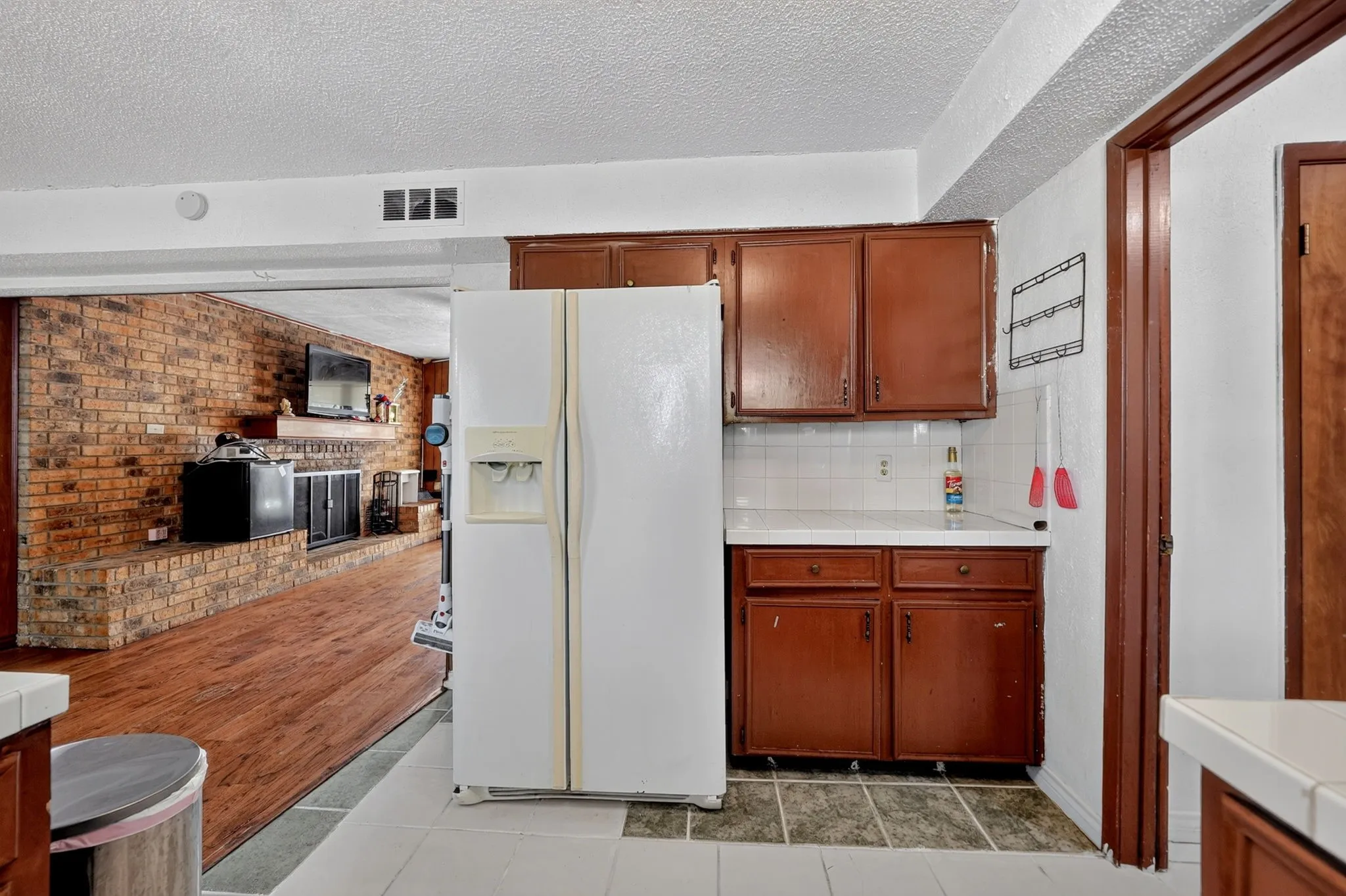 Kitchen featuring wood-finish cabinetry, tile backsplash, and a white refrigerator