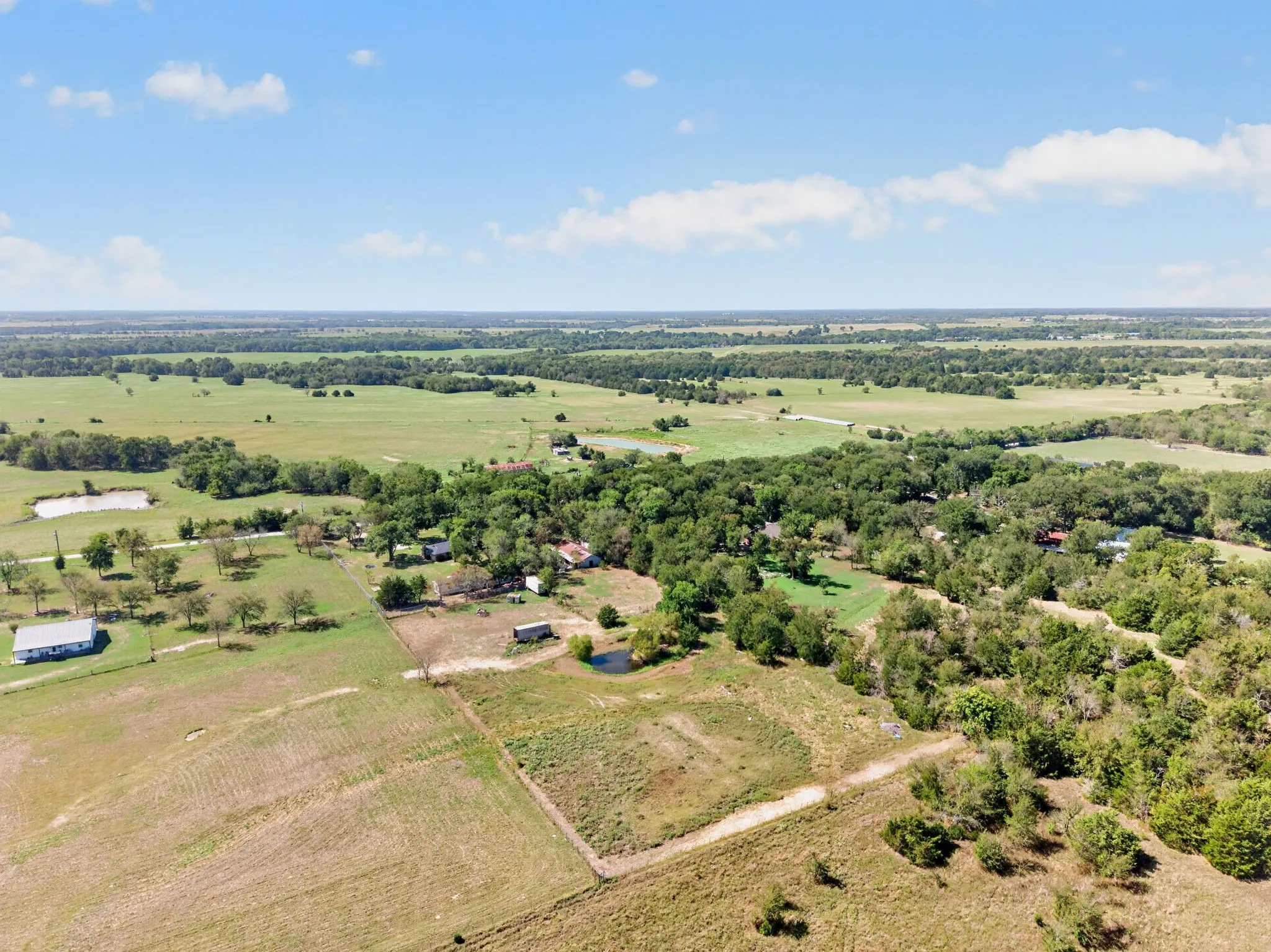 Expansive rural landscape featuring scattered residences, mature trees, and multiple water features