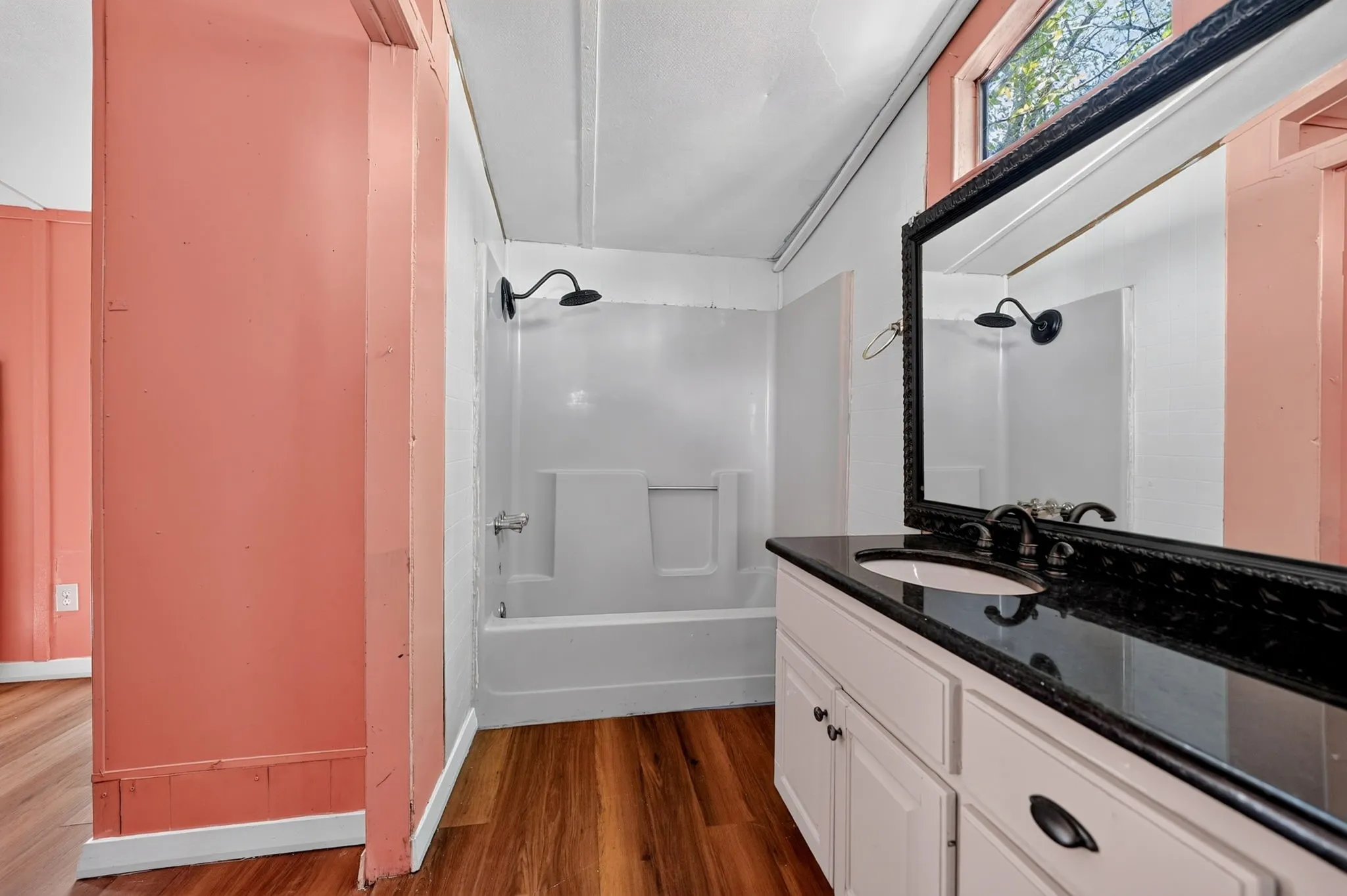 Vanity with a dark countertop, white cabinetry, undermount sink, and dark-finish faucet