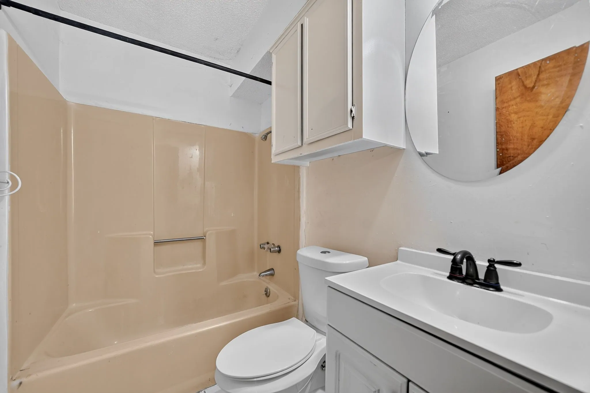 White vanity with integrated sink, black-finish faucet, and a circular wall mirror