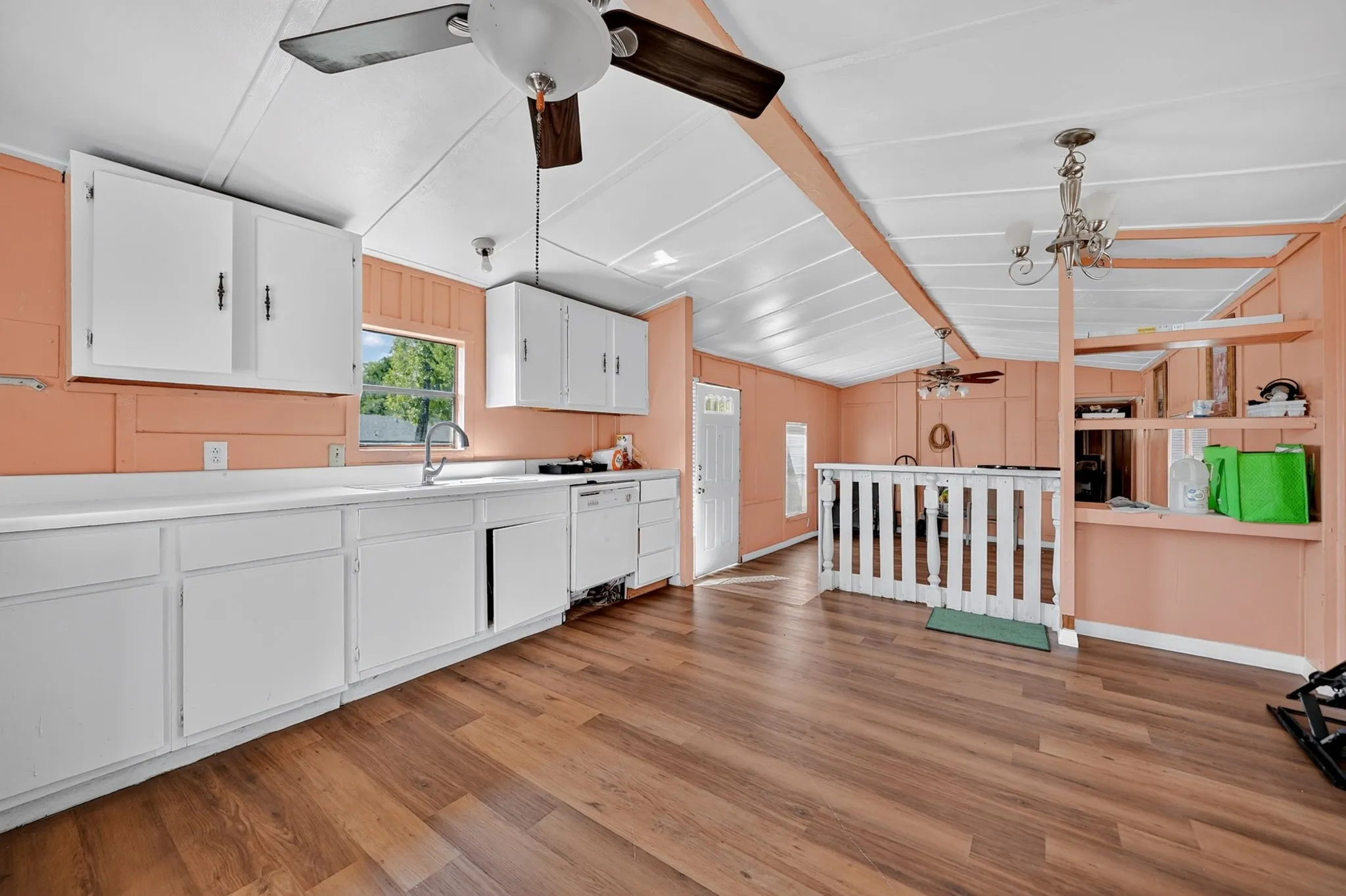 Kitchen featuring a long counter space, white cabinetry, a double basin sink with a high-arc faucet, and wood-finish flooring