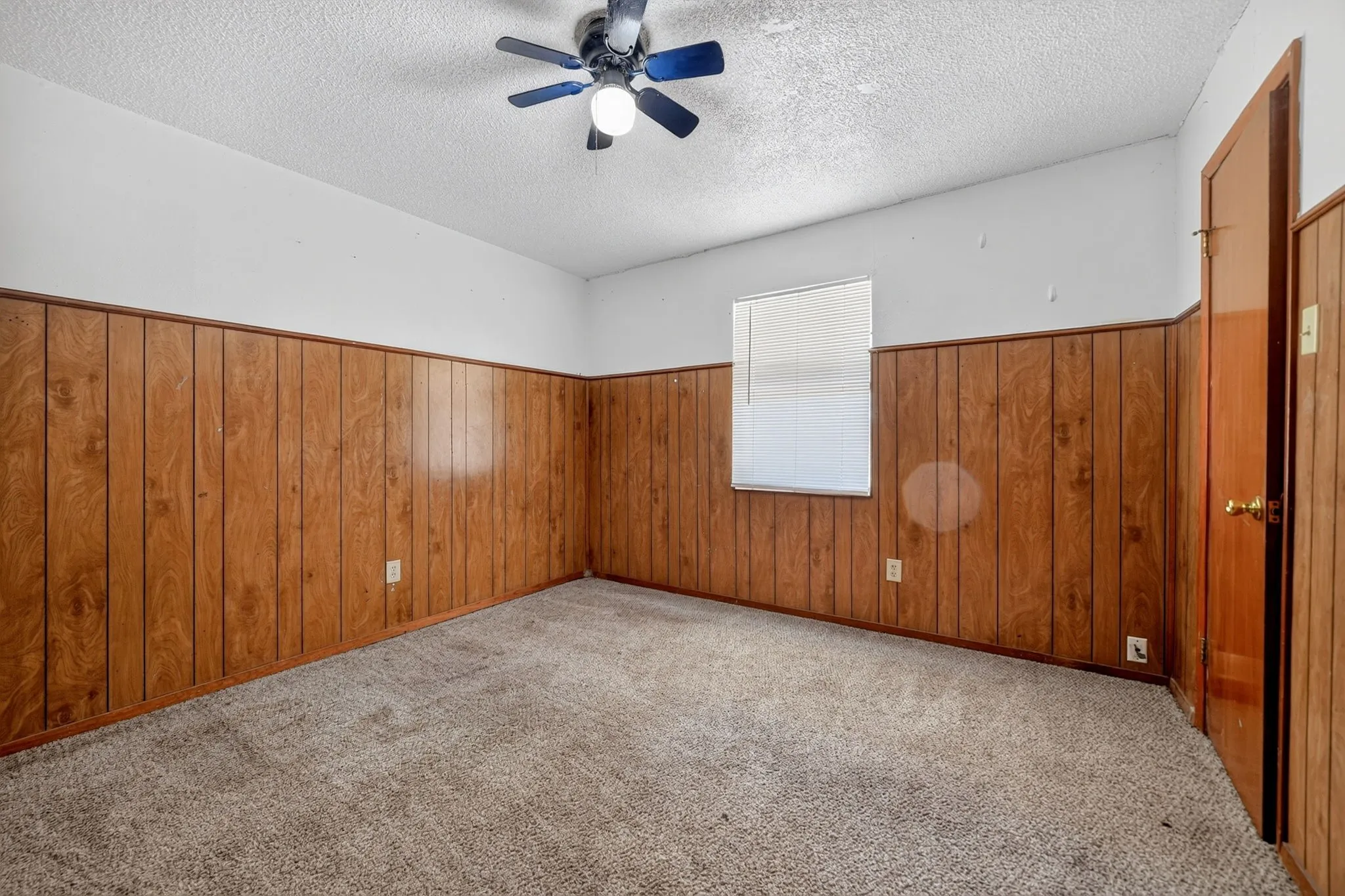 Carpeted flooring with wood paneling and a ceiling fan