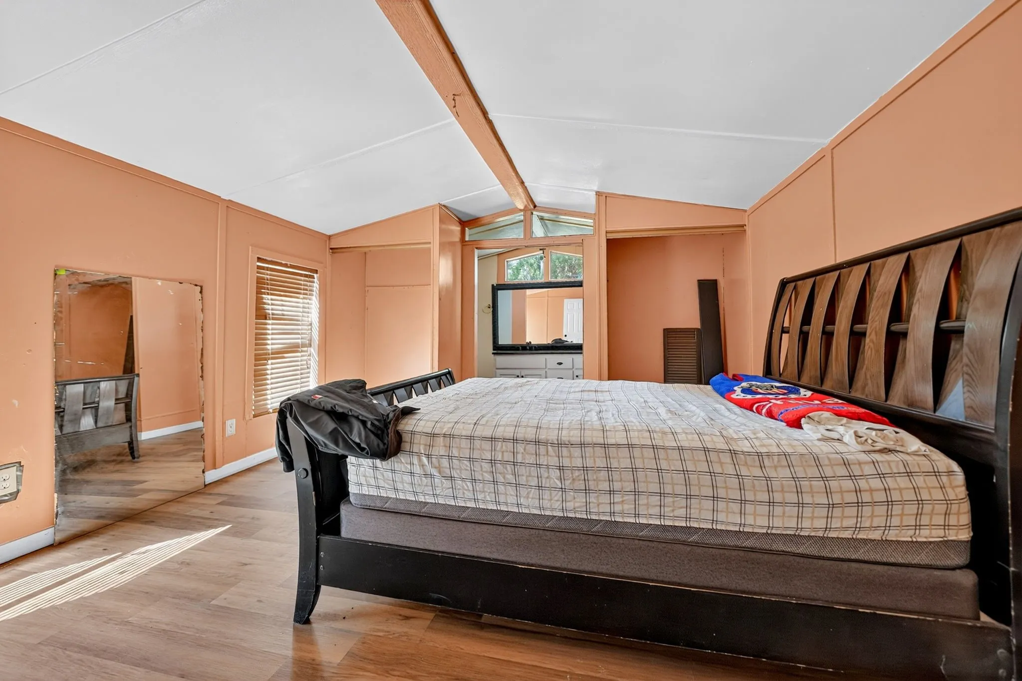 Wood-finish flooring, a window with blinds, and an open doorway
