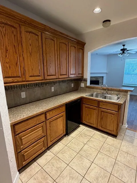 Kitchen featuring wood cabinetry, a double basin stainless steel sink, tile flooring, and a stone-finish countertop